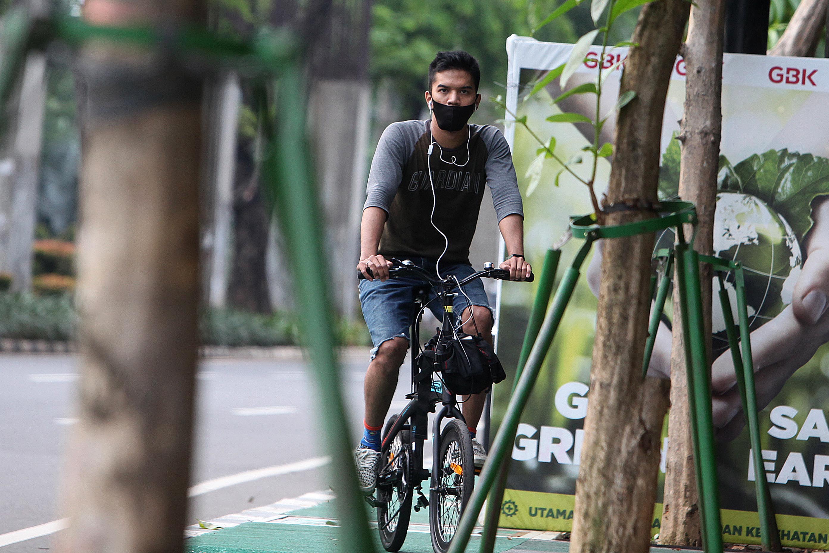 Warga olahraga bersepeda di GBK Senayan dengan memakai masker
