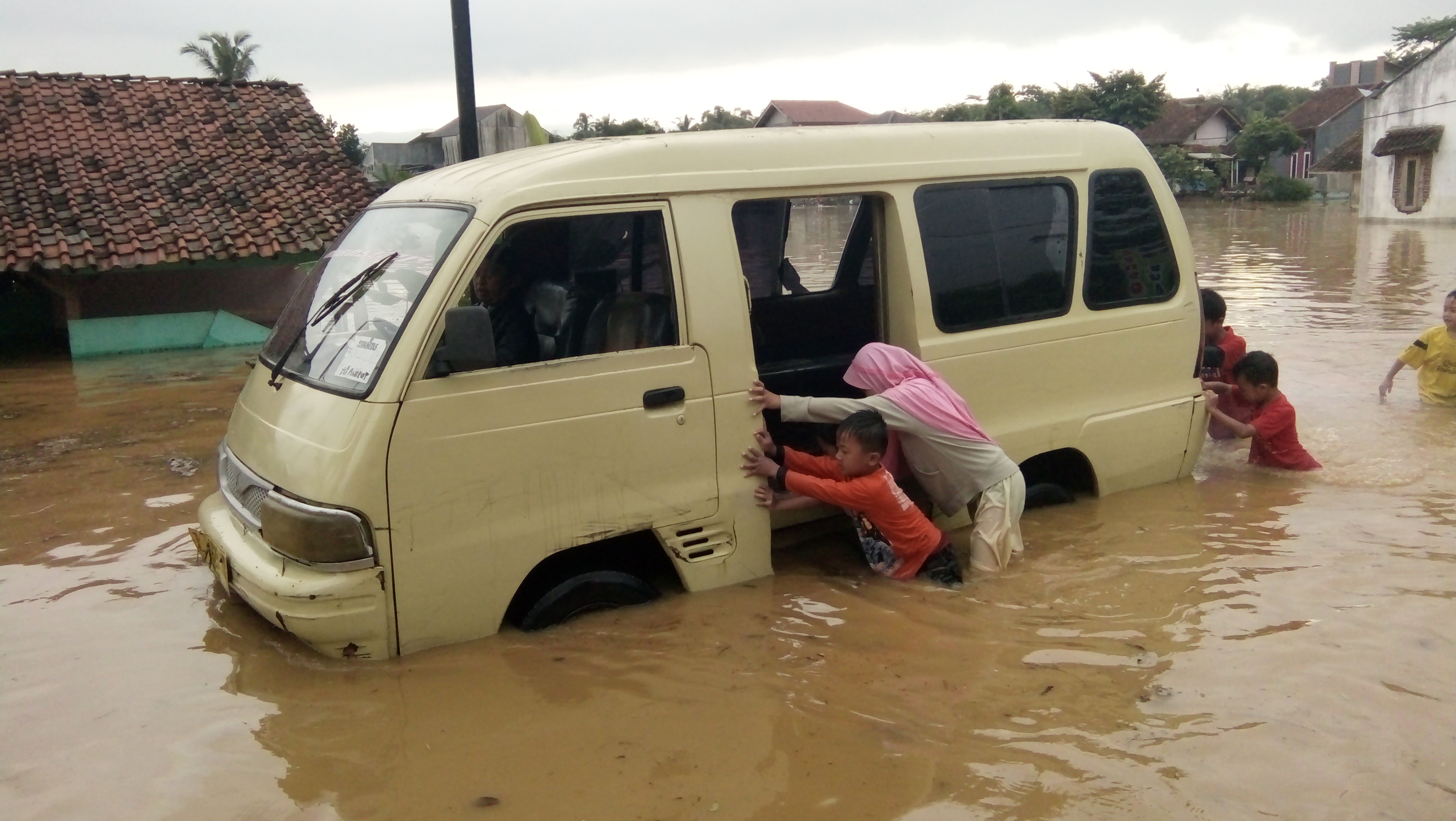 Warga mendorong kendaraan yang mogok di tengah banjir luapan Sungai Citanduy di Kecamatan Sukaresik, Kabupaten Tasikmalaya, Rabu (10/6/2020)