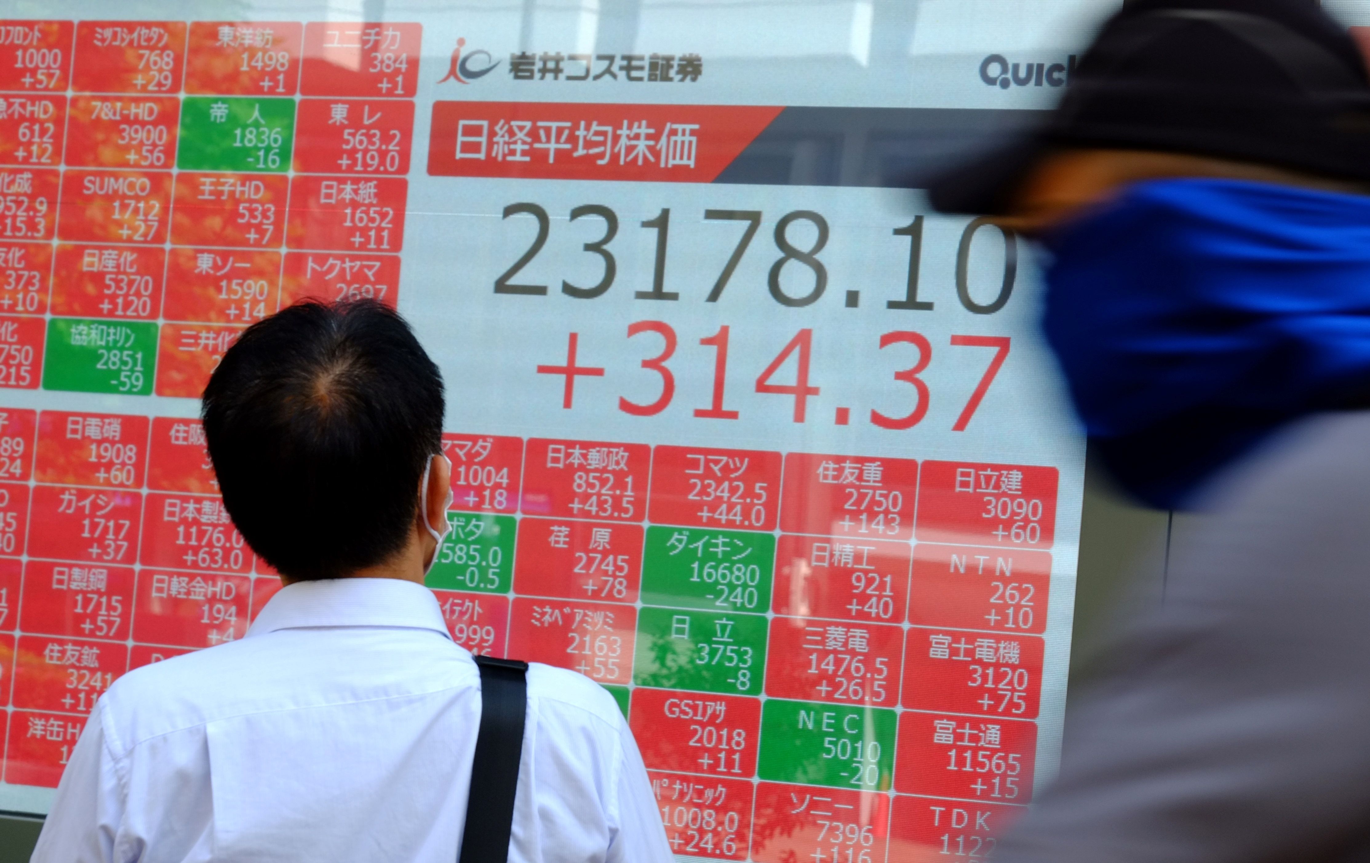 Pejalan melinta pada layar elektronik perdagangan bursa saham Jepang.