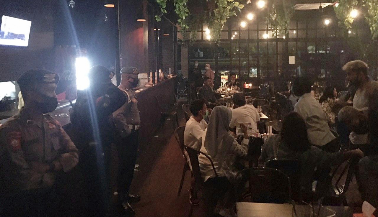 Polisi berjaga di kafe Big Brown Kota Ternate, Maluku Utara yang ditutup karena melanggar peraturan selama pandemi covid-19.