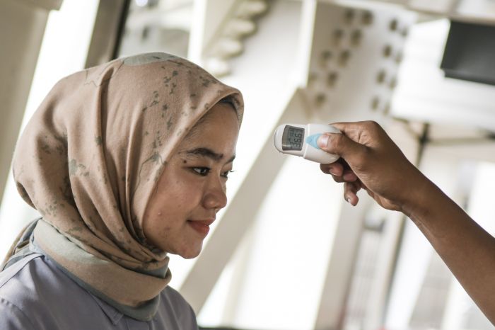 Petugas memeriksa suhu tubuh calon penumpang LRT (Light Rail Transit) di Stasiun LRT Velodrome, Jakarta  