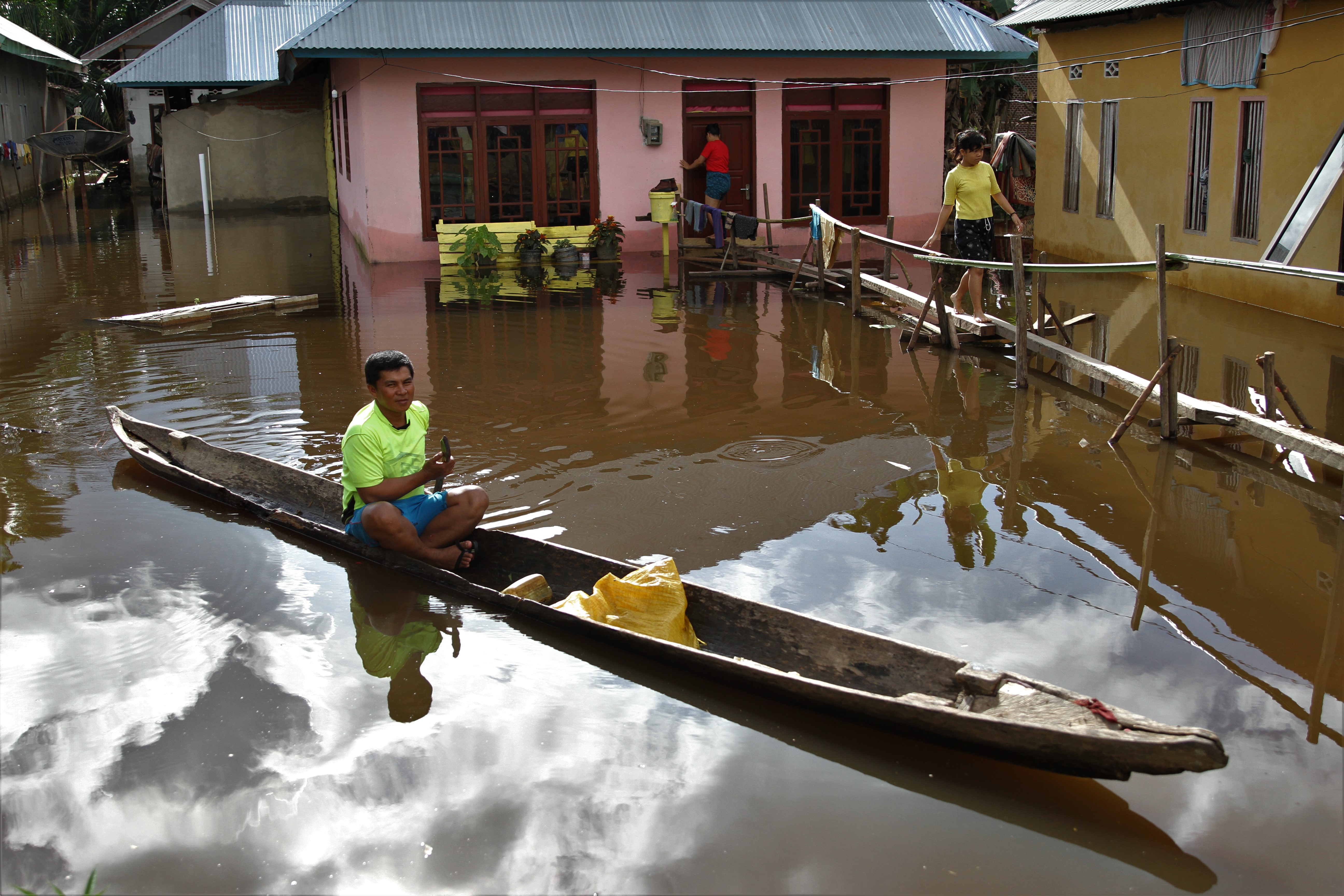 Warga melintas dengan menggunakan perahu di dekat rumahnya yang terendam banjir di Desa Rumbia, Kecamatan Bondoala, Konawe