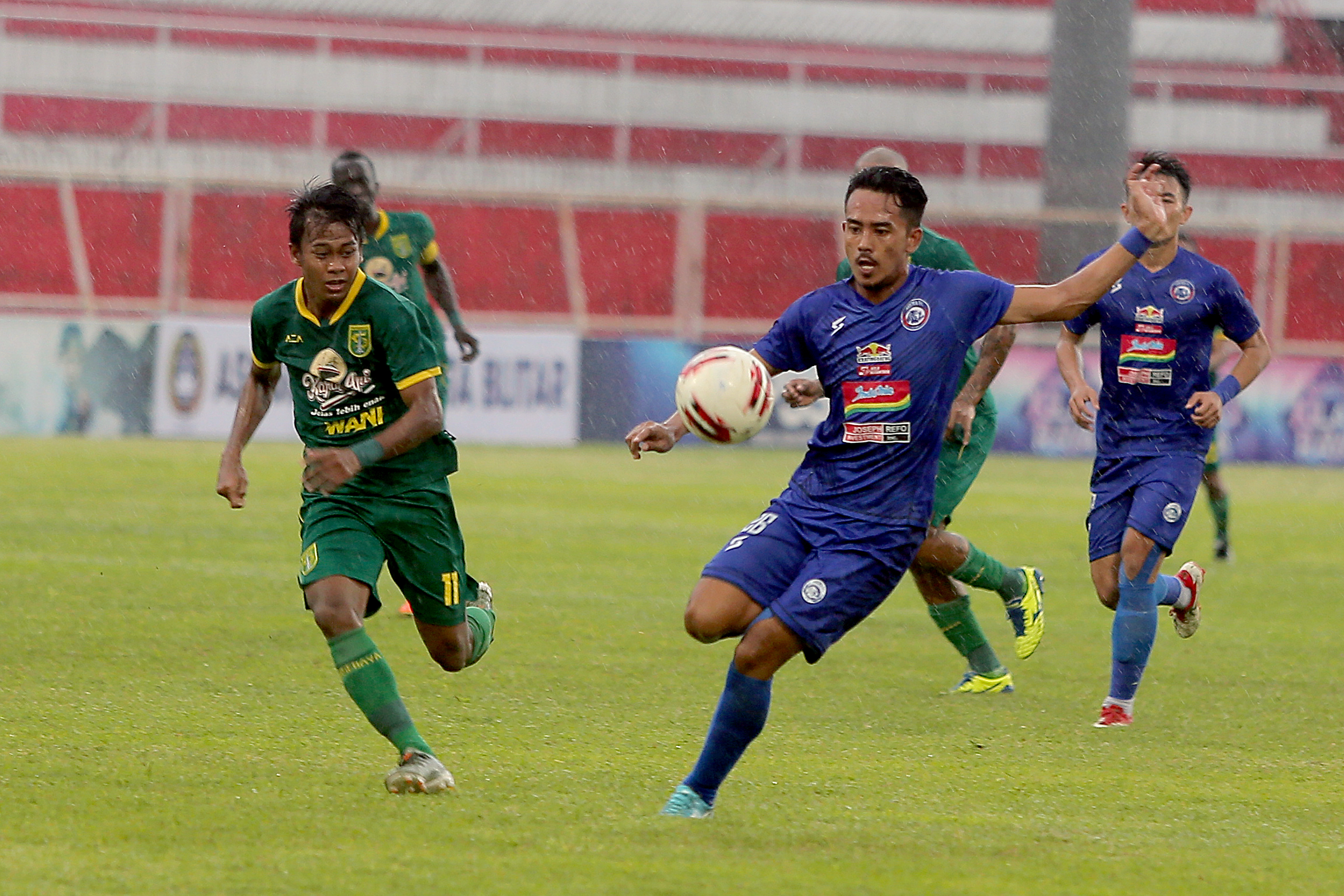 Pemain Arema FC menggiring bola dan melewati hadangan pemain Persebaya dalam laga Piala Gubernur Jawa Timur.