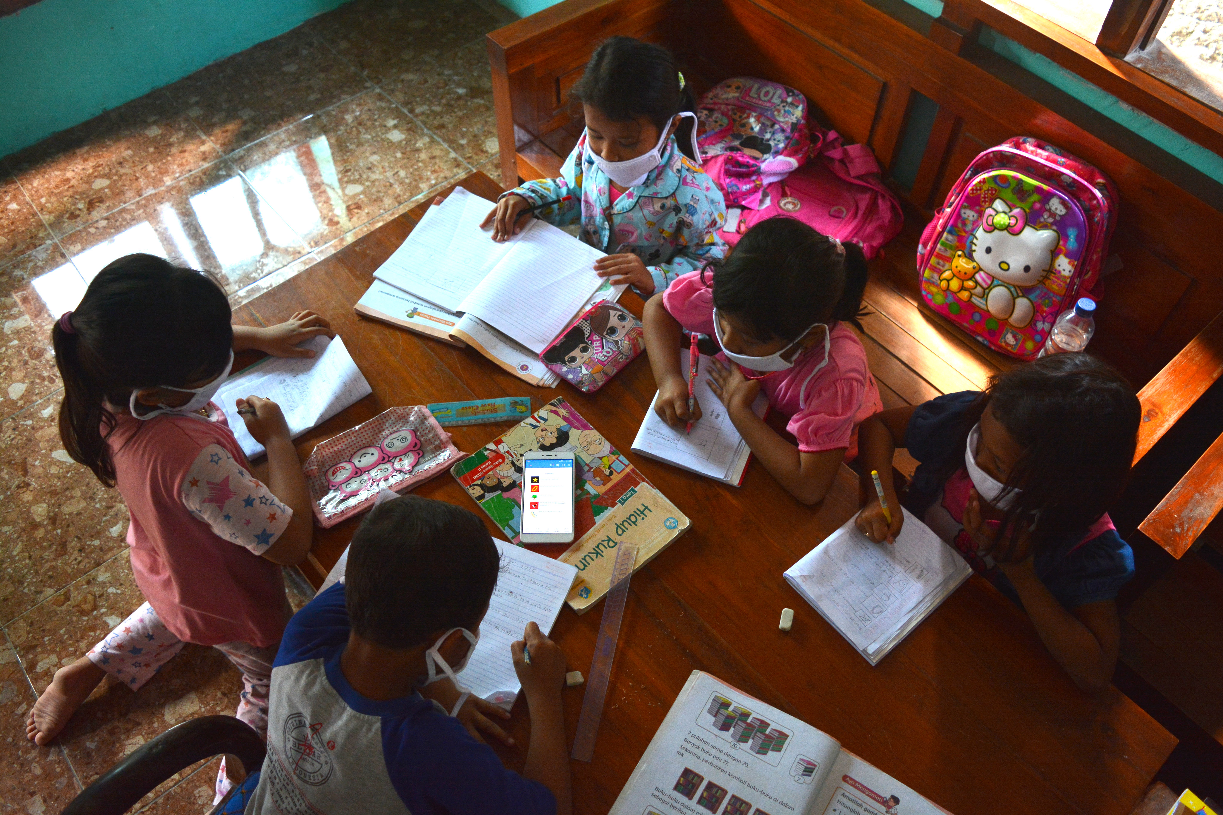 Sejumlah siswa SDN Marmoyo mengerjakan tugas dengan berkelompok menggunakan gawai secara bergantian di rumah warga Desa Marmoyo, Jawa Timur.