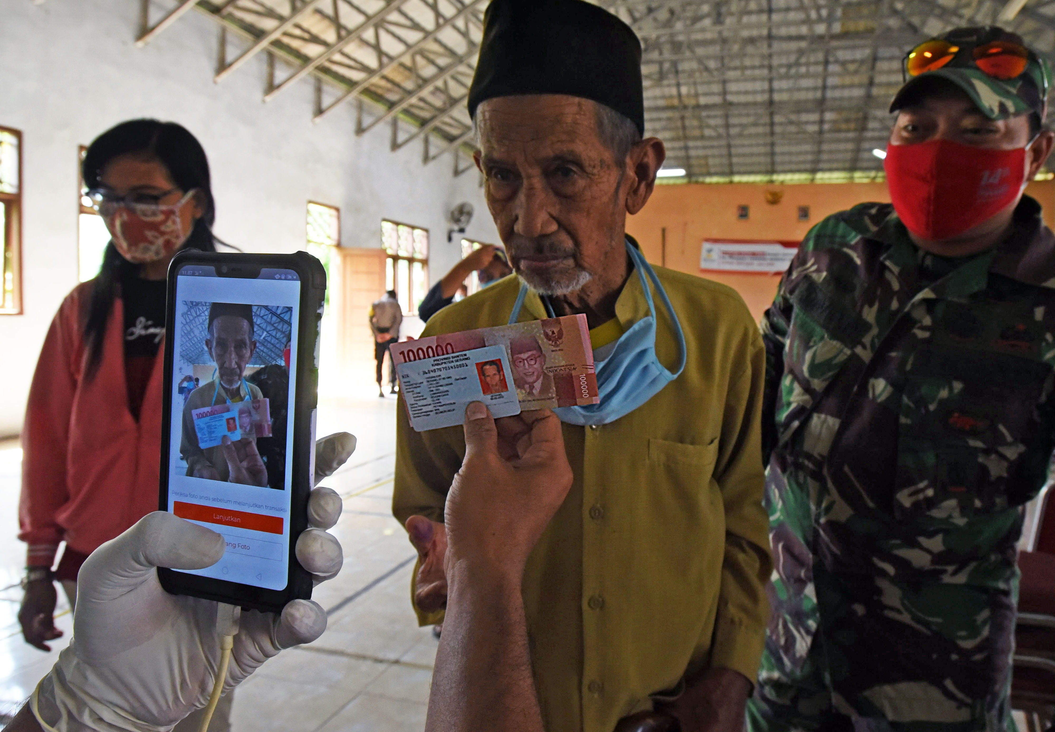 Warga penerima manfaat difoto petugas saat penyaluran bantuan sosial tunai di Kampung Gedong, Bojonegoro, Serang, Banten, Sabtu (30/5/2020).