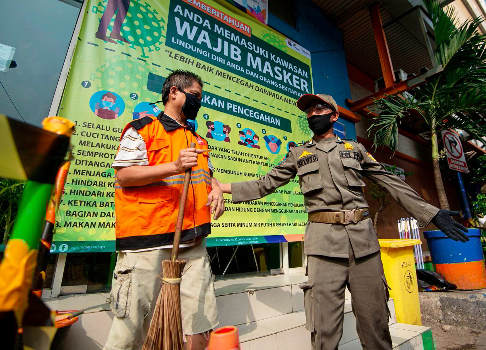 Petugas Satpol PP mengawasi pelanggar aturan pembatasan sosial berskala besar yang melaksanakan sanksi kerja sosial