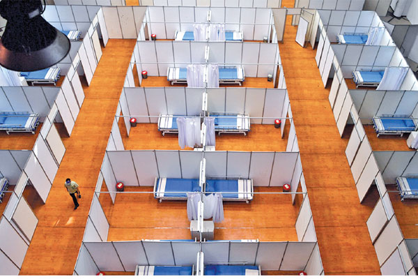 Pekerja melintas di antara bilik kamar di Sarana Olaraga Tridharma yang dijadikan ruang isolasi mandiri covid-19 di Gresik, Jawa Timur, 