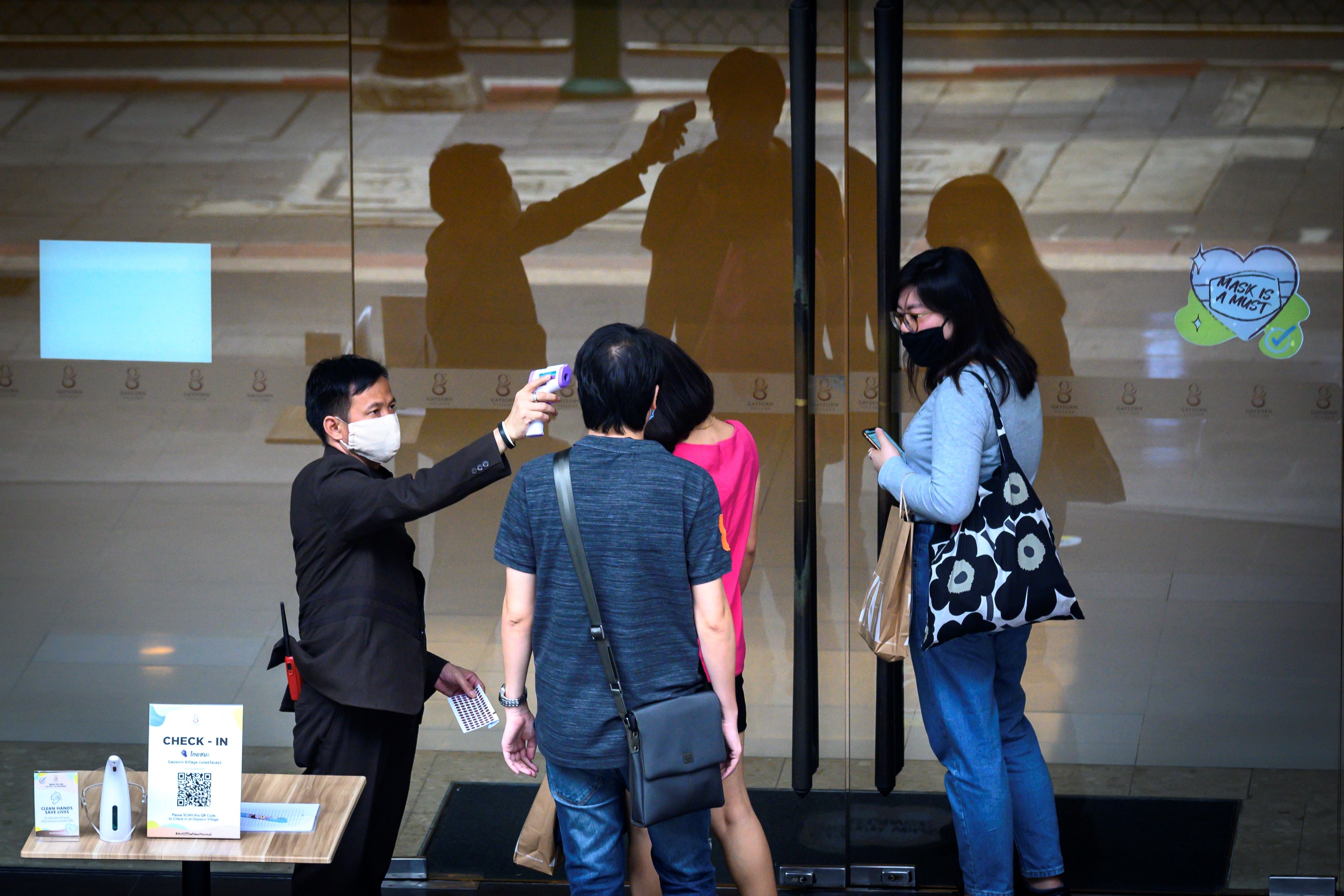  Seorang penjaga keamanan pusat perbelanjaan mengukur suhu pengunjung pencegahan terhadap penyebaran covid-19 di Bangkok, Thailand.