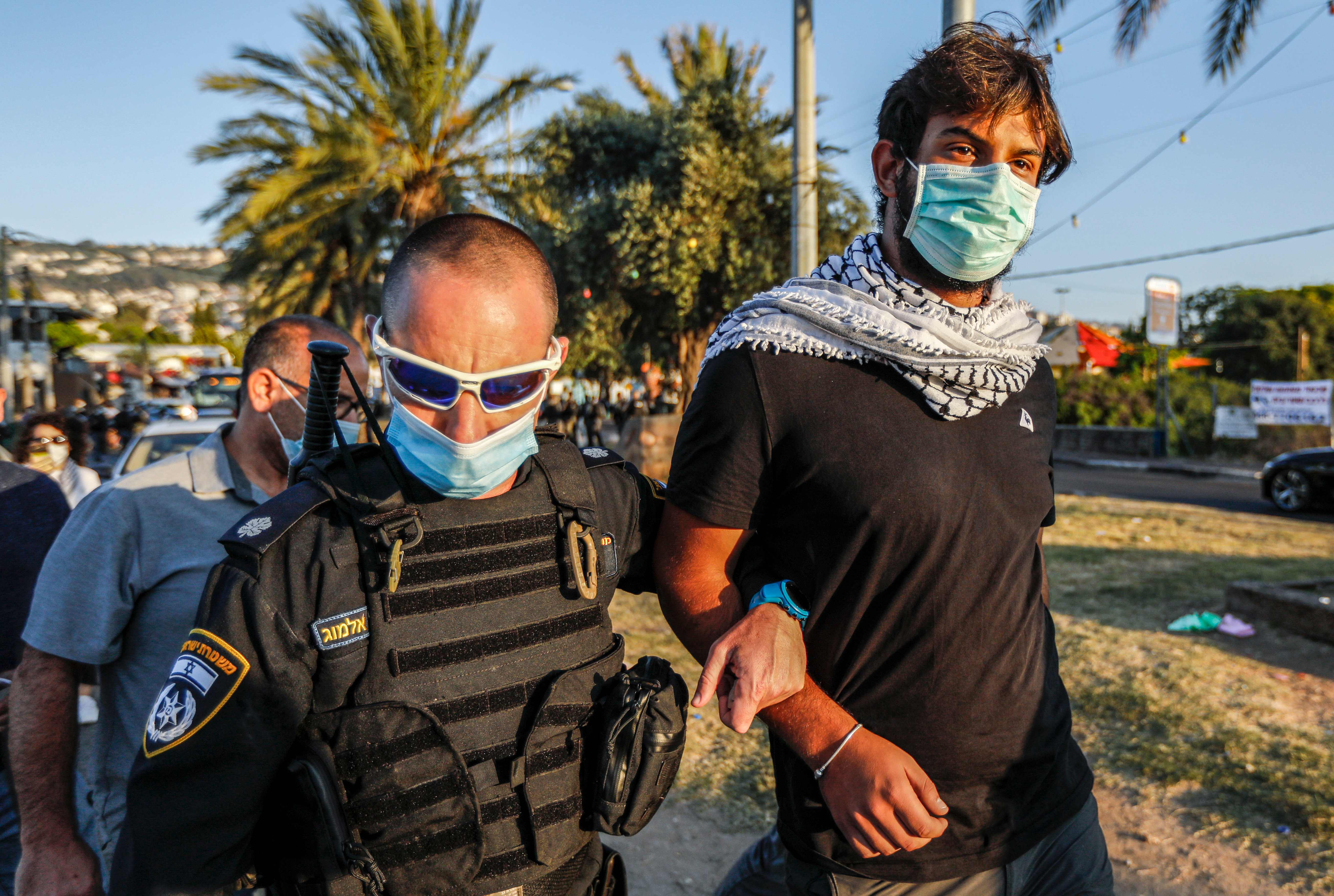 Seorang polisi Israel menahan seorang demonstran yang protes rencana Israel mencaplok bagian-bagian Tepi Barat, di kota Arara, Israel Utara.