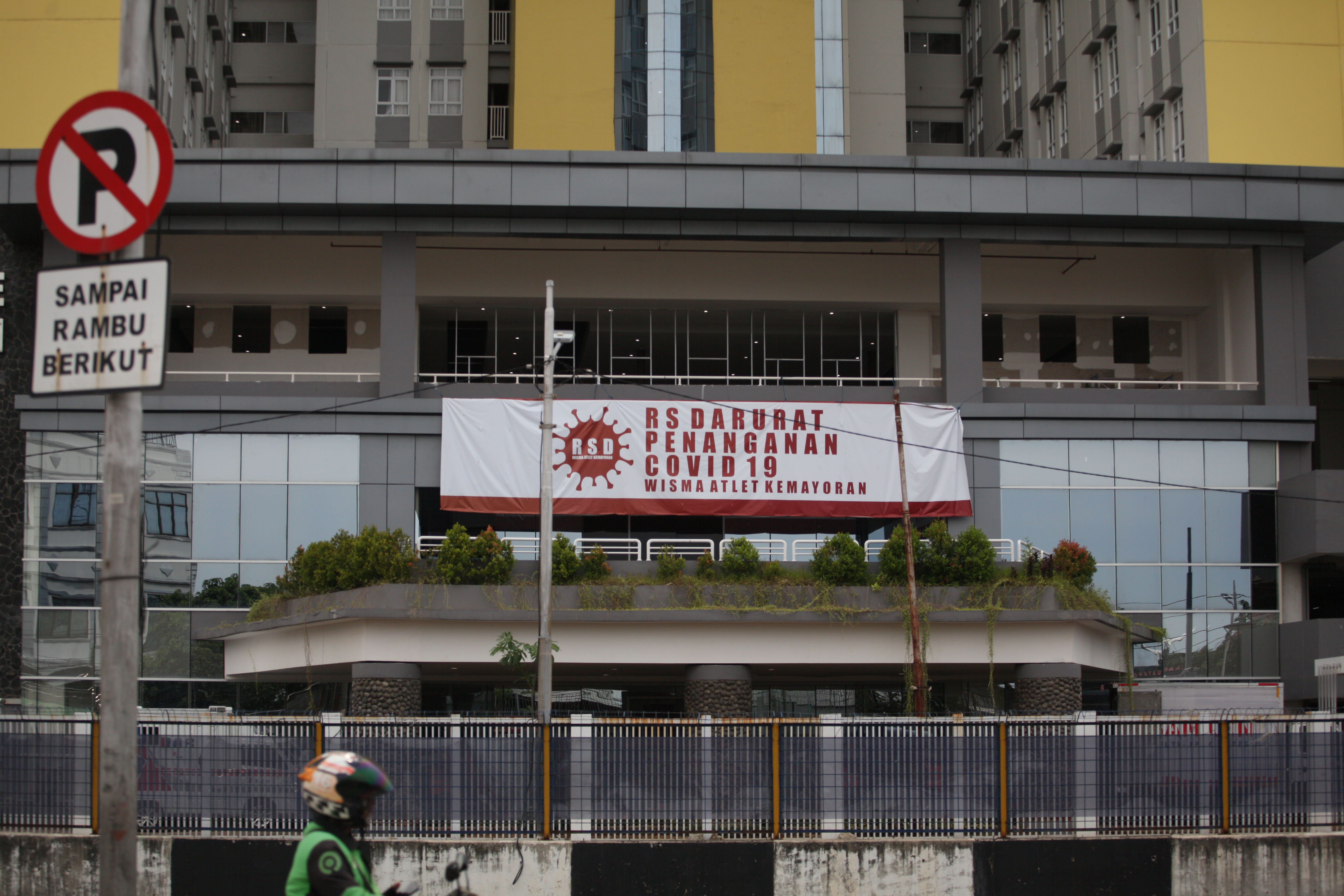 Warga melintas di depan Rumah Sakit Darurat Penanganan COVID-19 Wisma Atlet Kemayoran, Jakarta, Senin (23/3/2020)