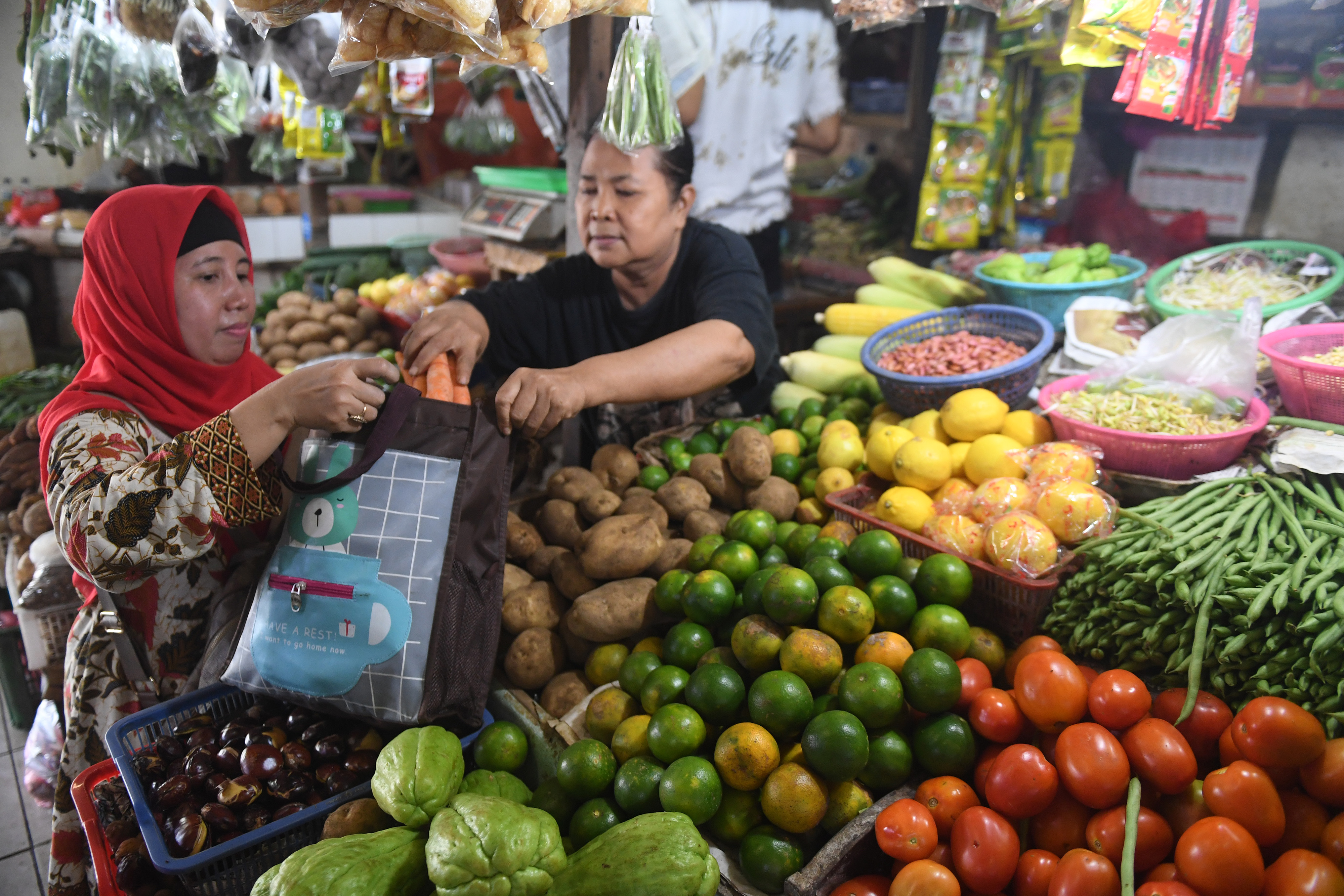  Pedagang memasukkan belanjaan ke dalam tas belanjaan saat bertransaksi di Pasar Tebet Barat Jakarta