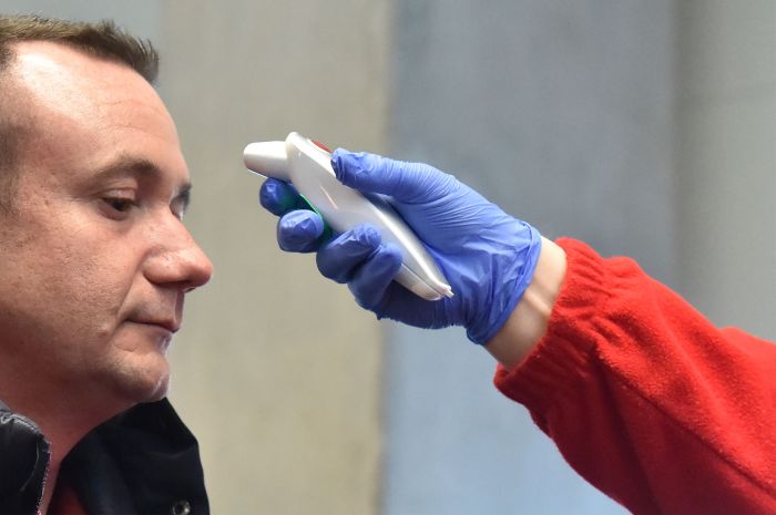 Seorang pekerja diperiksa suhu tubuhnya sebelum memasuki Bandara Liszt Ferenc, Budapest, Hongaria.