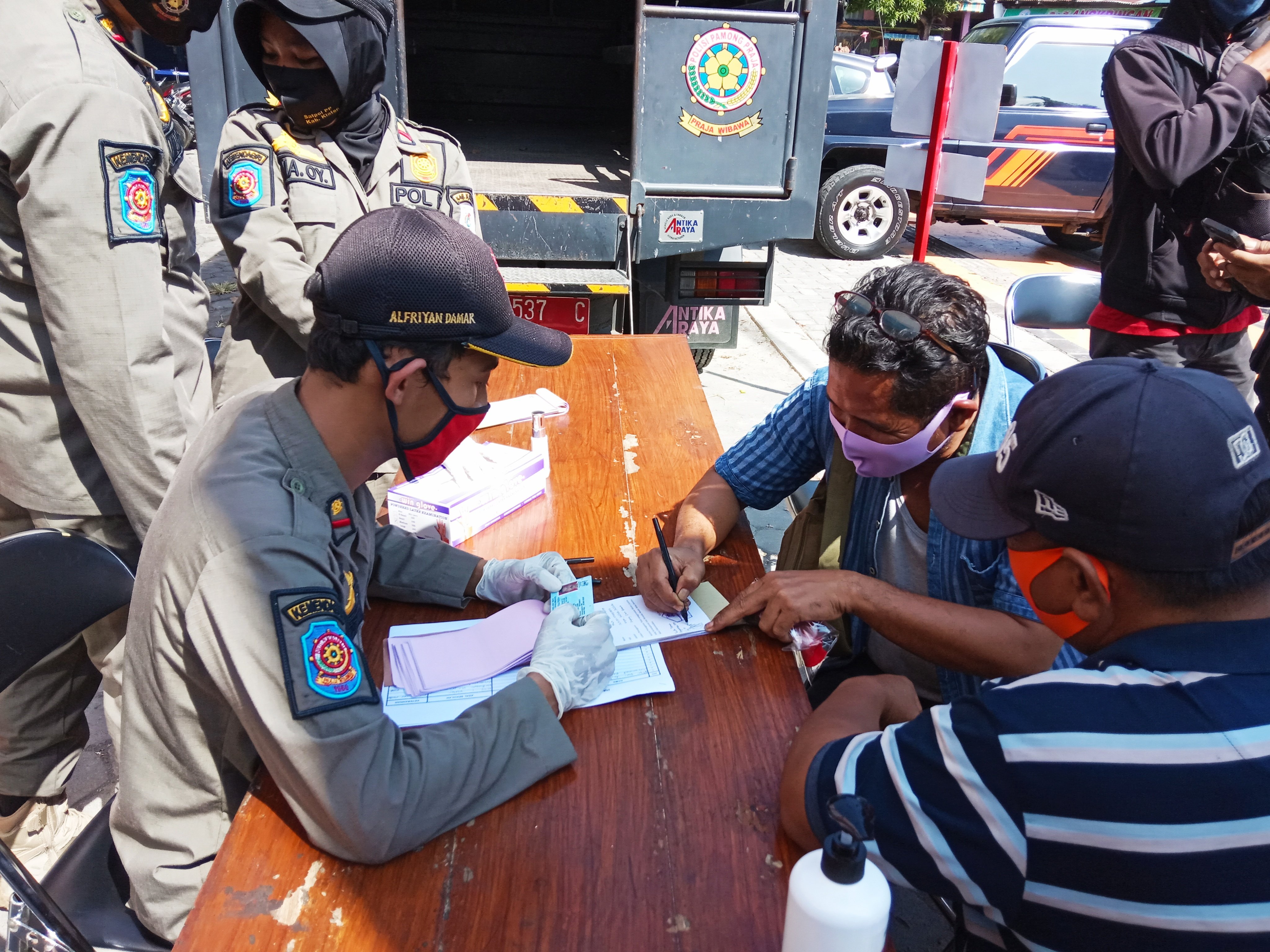 Warga terjaring operasi telah memakai masker saat mengambil KTP yang ditahan petugas Satpol PP di Klaten, Jawa Tengah.