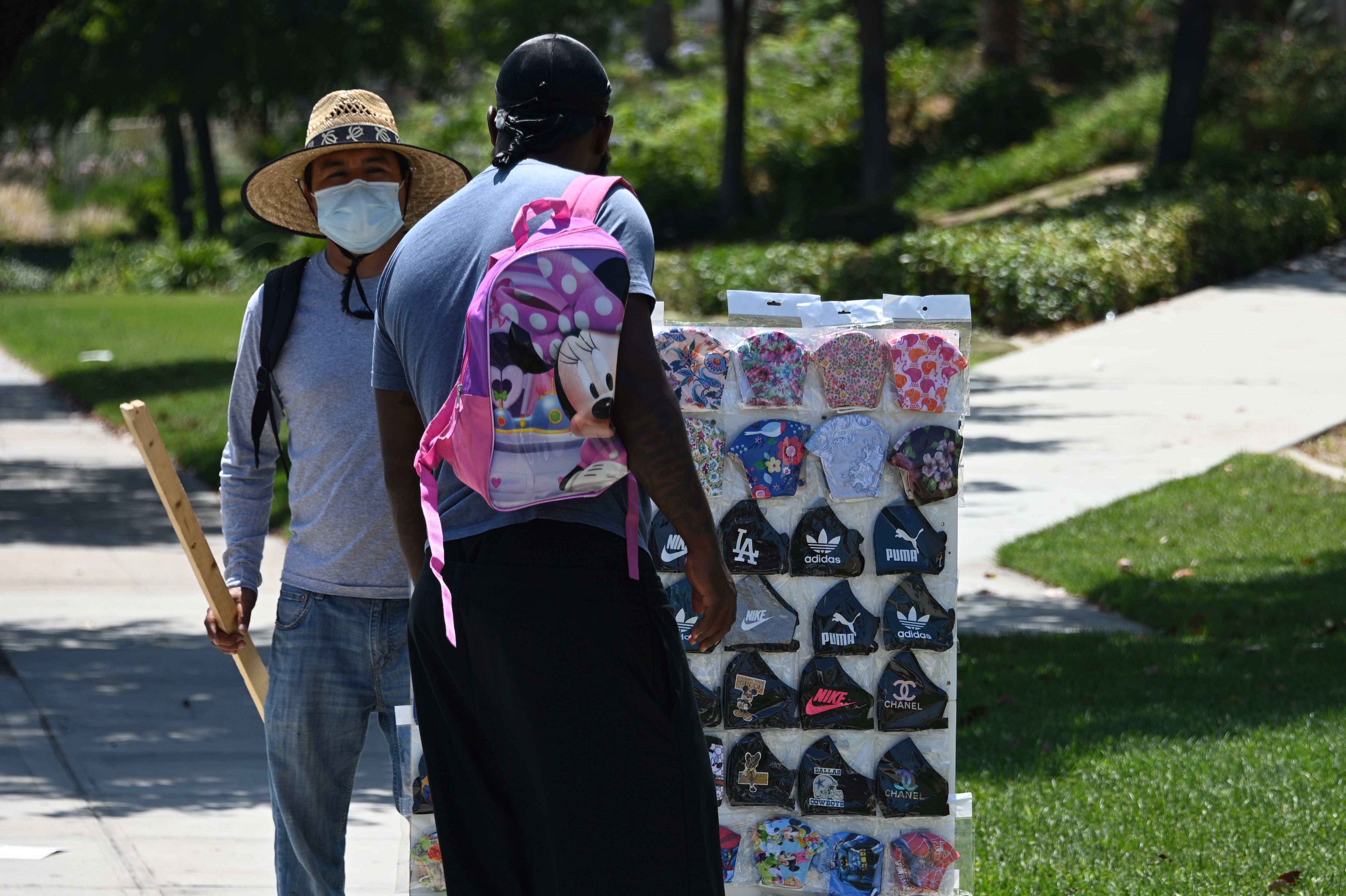 Seorang pria melihat masker yang ditawarkan seorang pedagang di Burbank, California, Amerika Serikat.