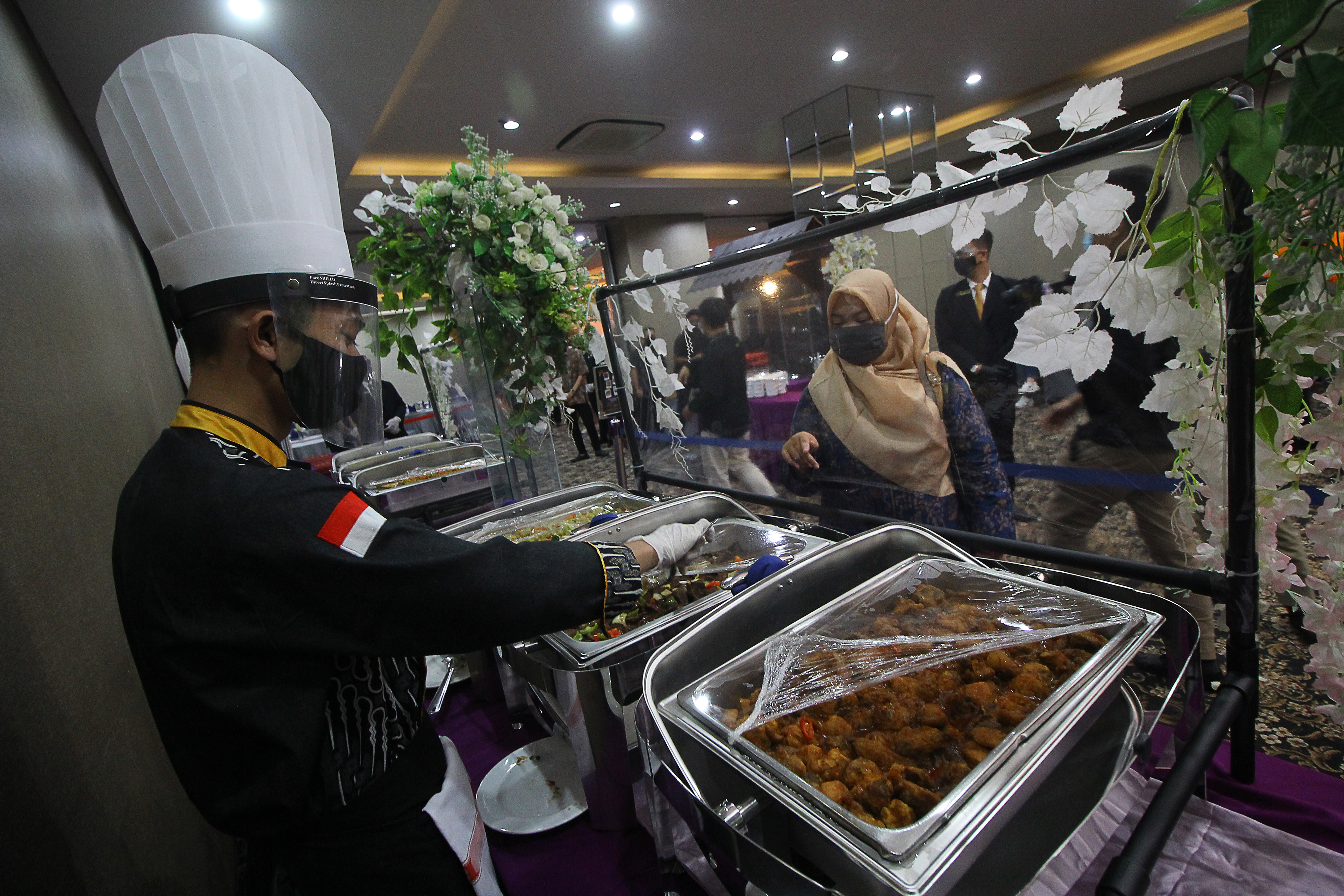 Juru masak mengenakan masker, pelindung wajah dan sarung tangan saat melayani tamu undangan pada simulasi resepsi pernikahan di masa normal 