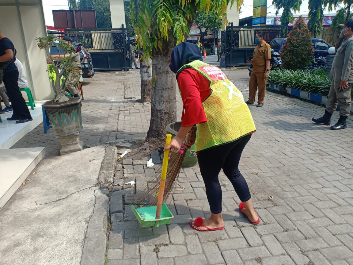 Warga tanpa memakai masker diberi sanksi dengan memakai rompi kuning dan menyapu di ruang publik.