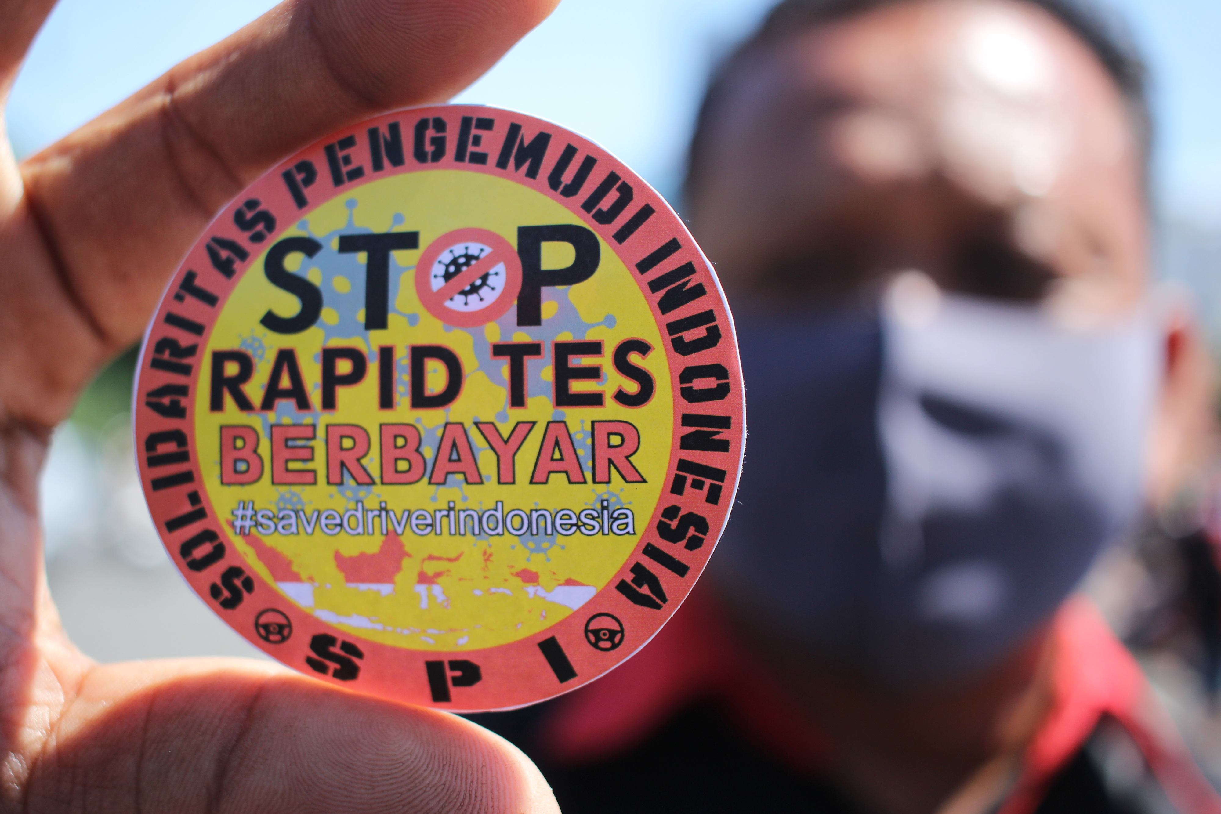 Sopir truk di Surabaya menunjukkan stiker Stop Rapid Test Berbayar saat berunjuk rasa.