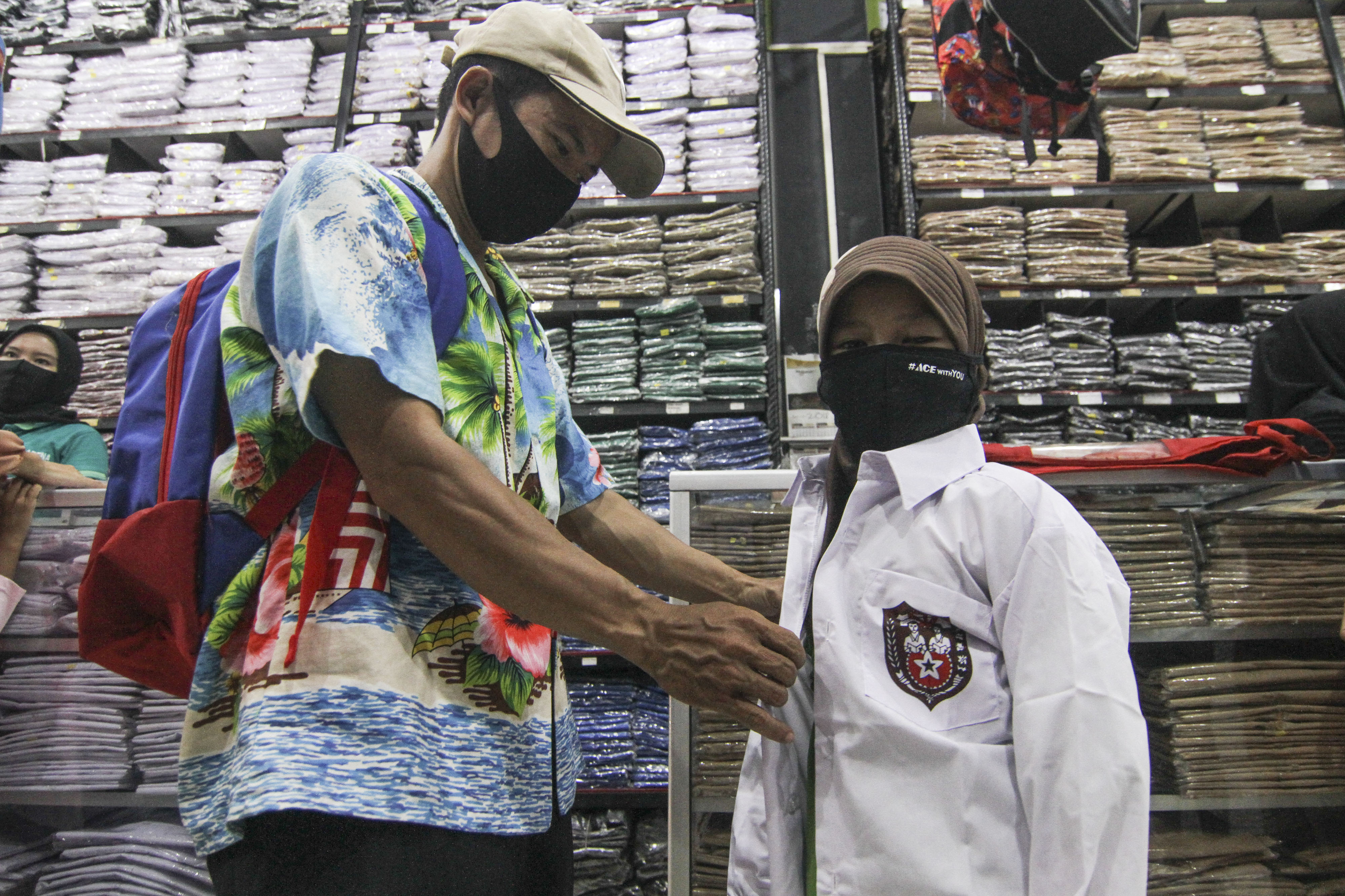 Seorang siswa sedang menjajal seragam sekolah