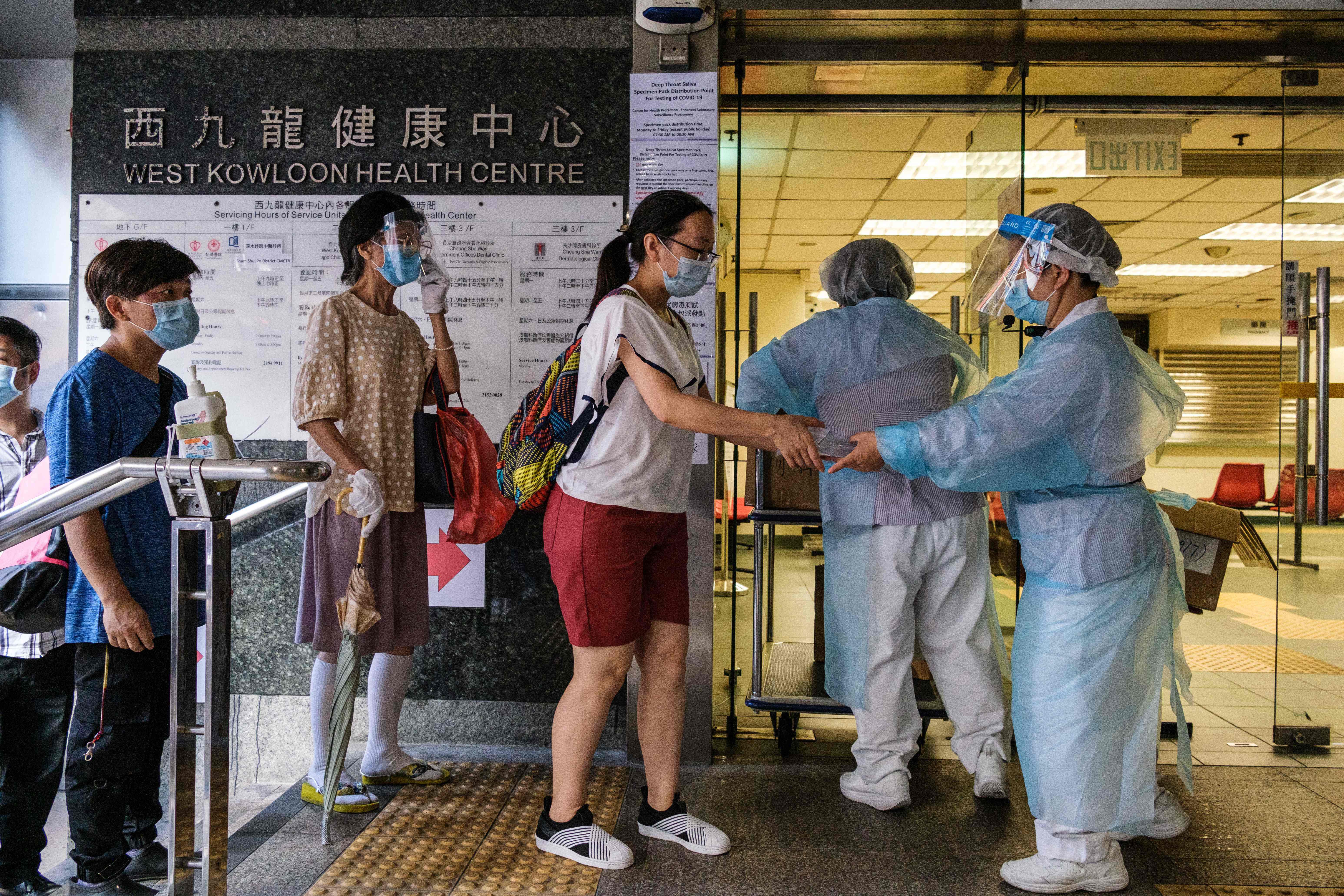 Petugas menyerahkan test kit covid-19 kepada warga di sebuah klinik pemerintah di Distrik Sham Shui Po, Hong Kong.