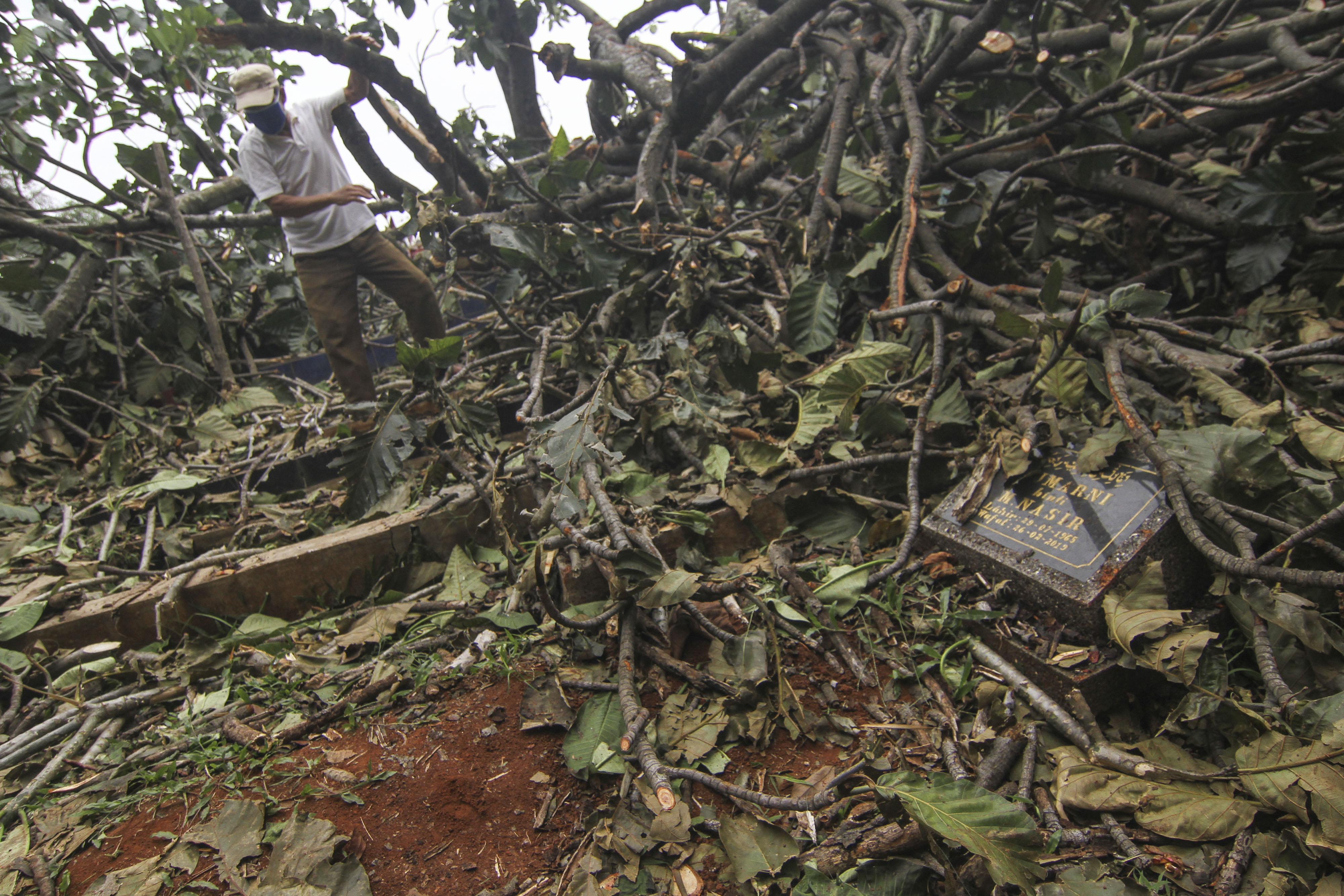 Warga mengecek makam keluarganya yang tertimpa pohon di TPU Cilangkap, Depok, Jawa Barat, Rabu (15/7/2020)