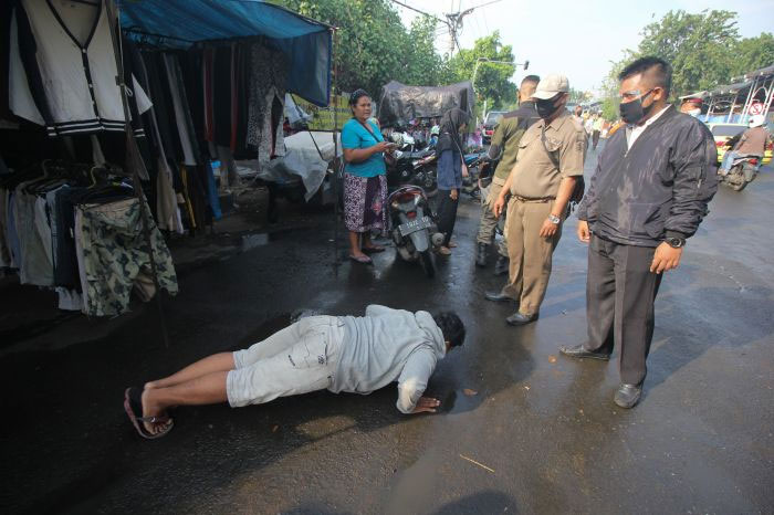 Petugas Satpol PP menghukum warga yang tidak mengenakan masker untuk push up saat Operasi Patuh Masker di Jalan Nyamplungan, Surabaya, Senin