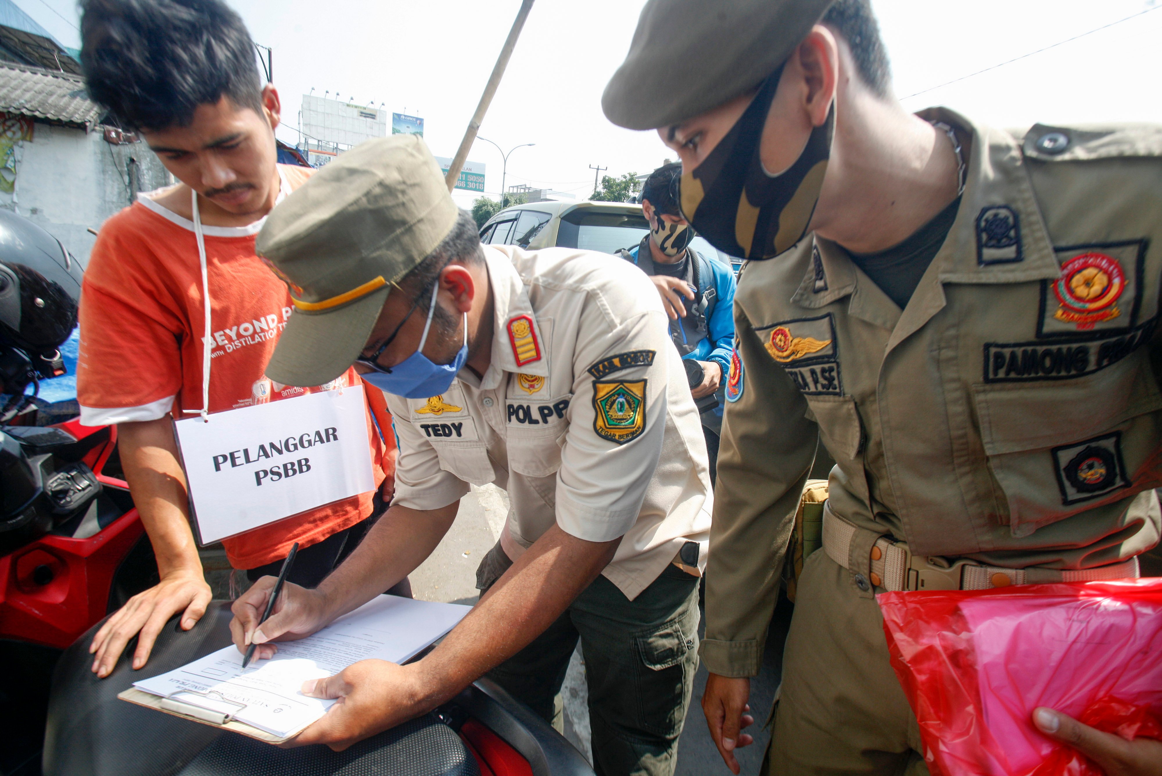 Petugas Satpol PP menilang warga yang tidak menggunakan masker di kawasan Pasar Cibinong, Kabupaten Bogor, Jawa Barat, Rabu (29/7).