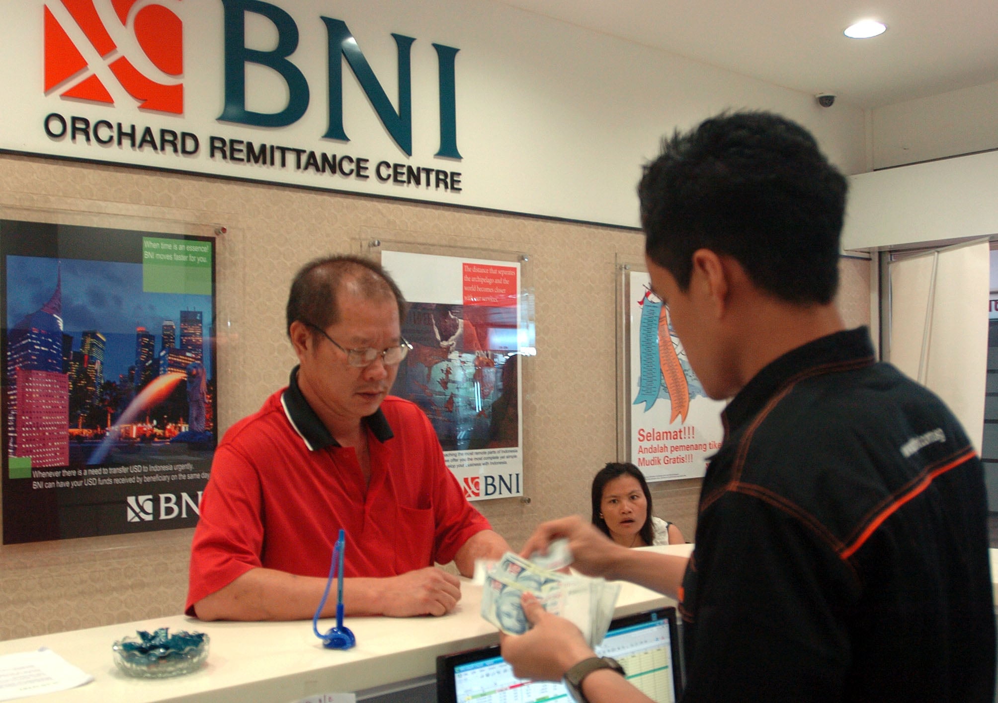 Teller melayani nasabah yang akan menggunakan fasilitas transfer antar negara (remittance), di BNI cabang Orchard, Singapura.
