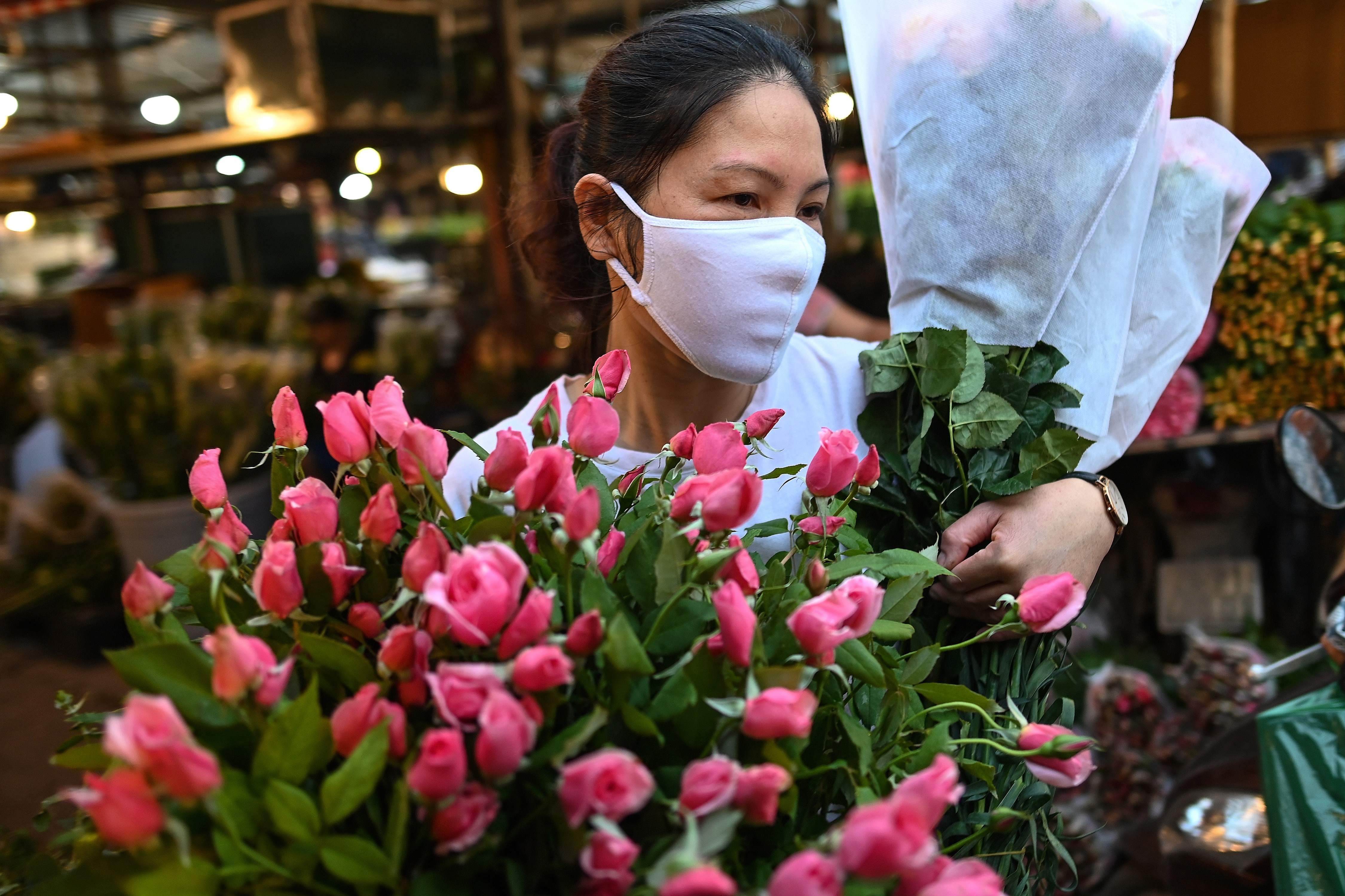 Seorang pedagang bunga di pasar bunga Quang Ba, Hanoi, Vietnam mengenakan masker untuk mencegah penyebaran covid-19.