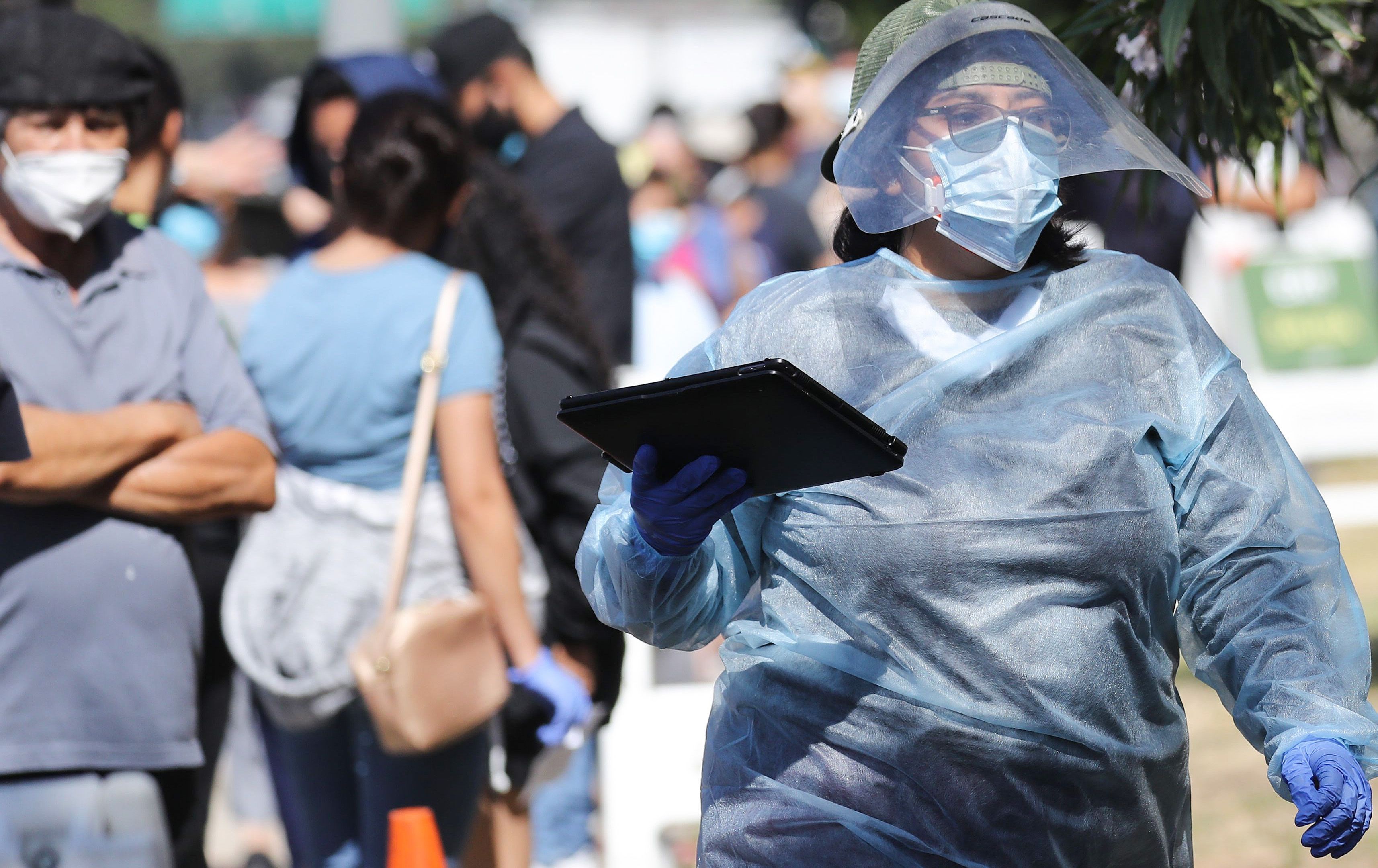 Seorang pekerja mengenakan alat pelindung diri memeriksa warga di pusat pengujian covid-19 di Lincoln Park, Los Angeles, California.