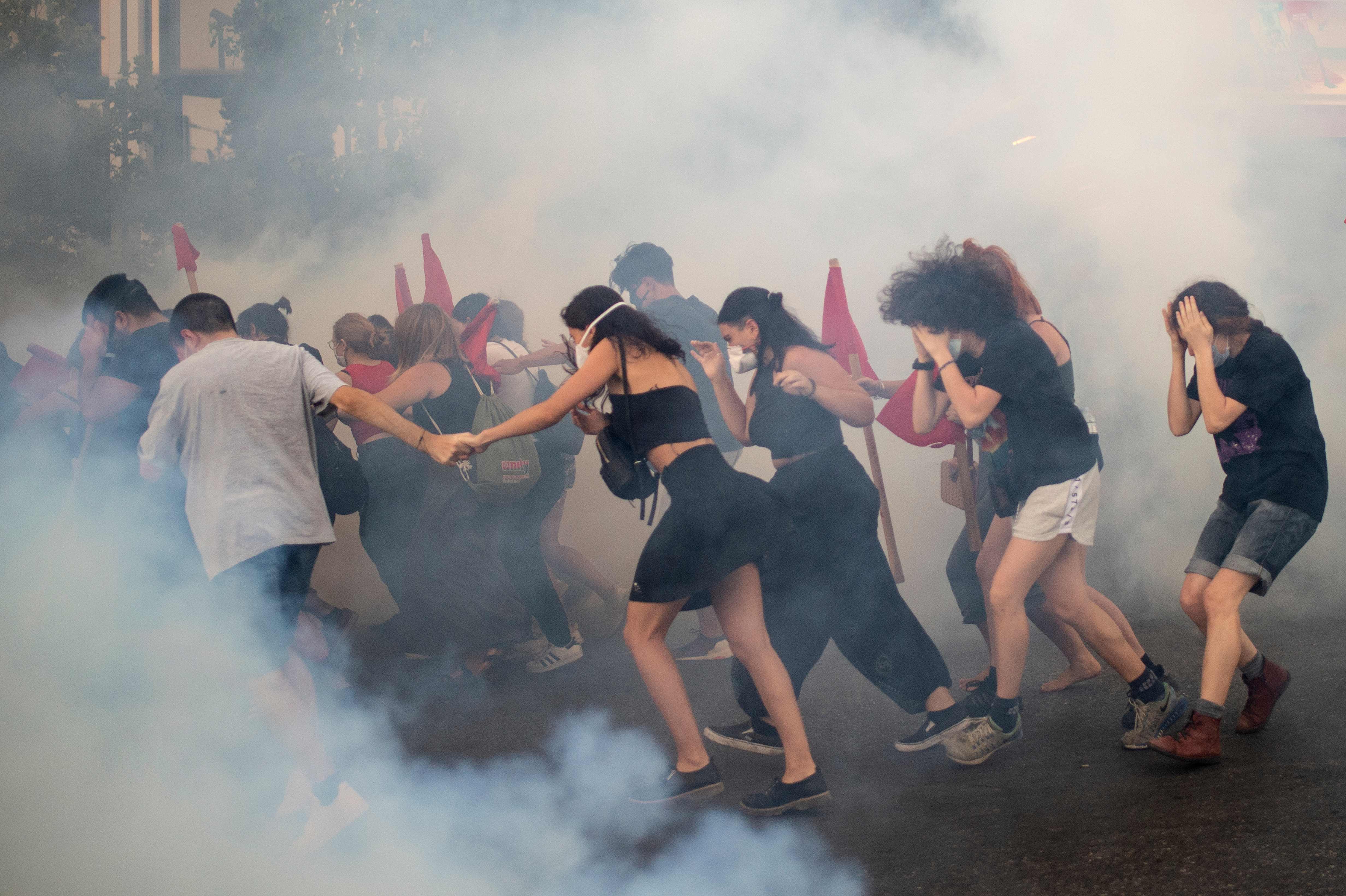 Para pengunjuk rasa berlari di tengah asap gas air mata selama bentrokan dengan polisi antihuru-hara (9/7/2020)