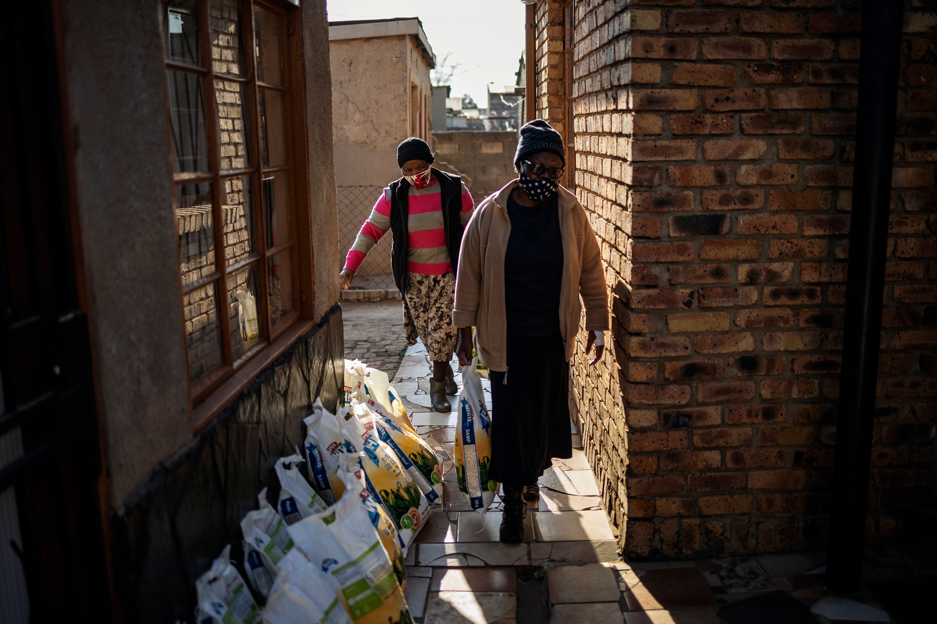 Para pensiunan membawa paket makanan yang didistribusikan oleh Meals on Wheels di Tsakane, Ekurhuleni (6/7/2020)
