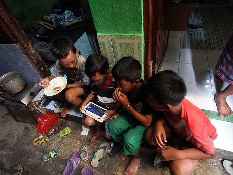 Anak-anak bermain gadget yang terkoneksi internetdi pemukiman gang sempit kawasan Kwitang, Jakarta Pusat