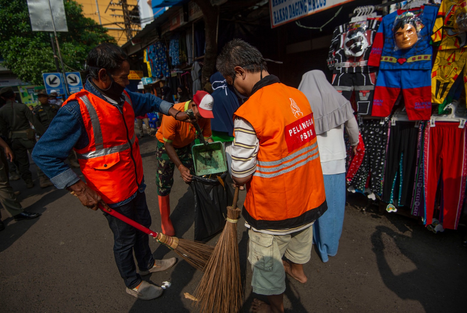 Sanksi kerja sosial dengan menyapu sampah di Pasar Jatinegara, Jakarta bagi pelanggar PSBB