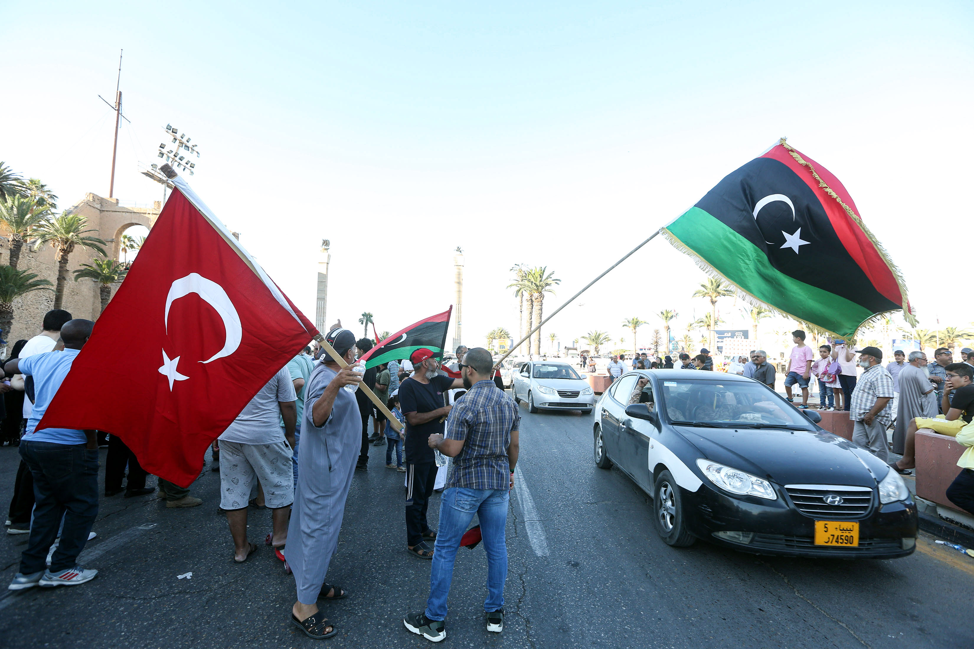 Warga mengibarkan bendera Turki dan Libia saat aksi demonstrasi di Tripoli.