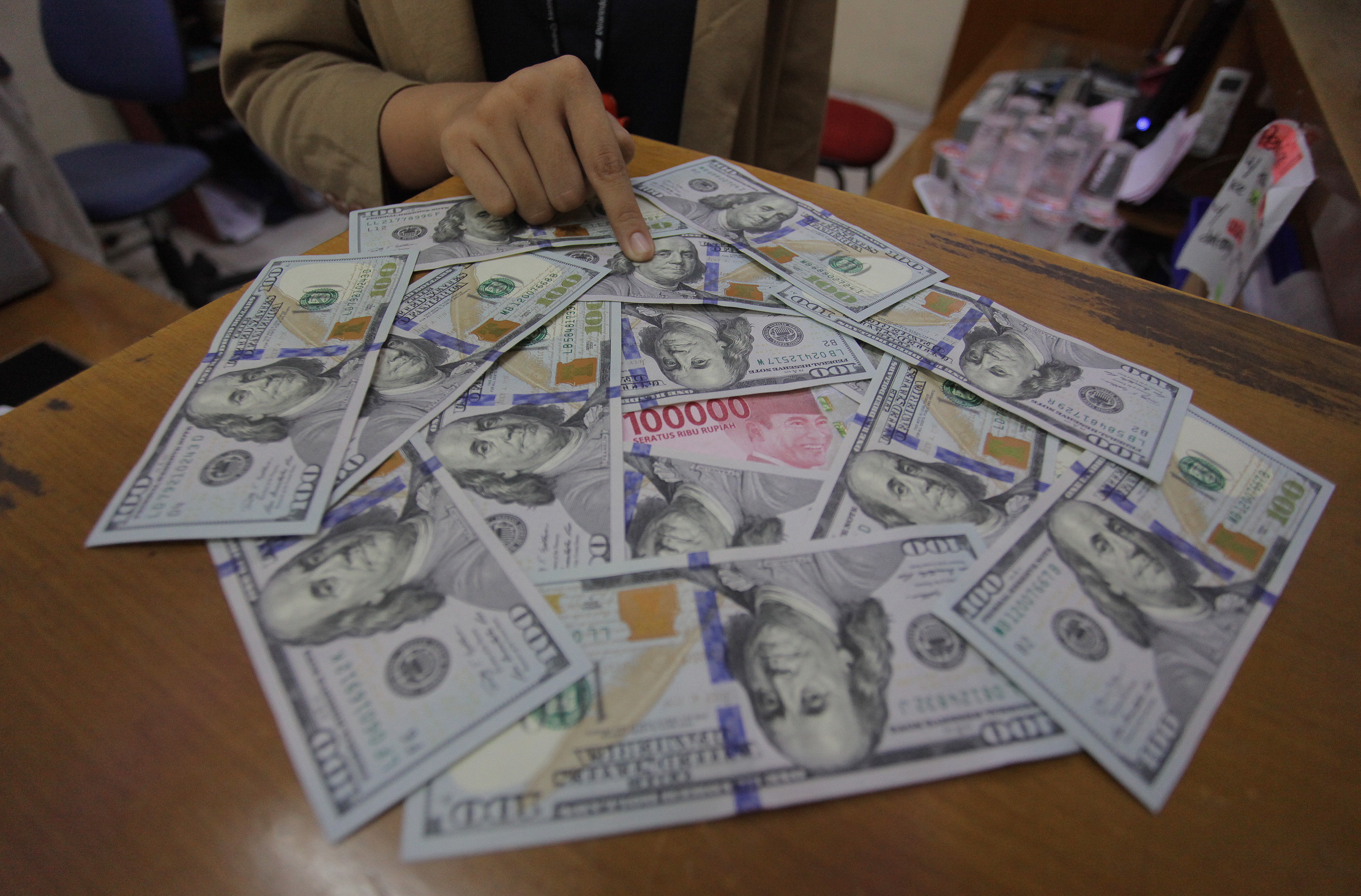 Karyawati menunjukkan mata uang rupiah dan dolar AS di salah satu gerai penukaran mata uang asing di Jakarta, Minggu (7/6/2020).