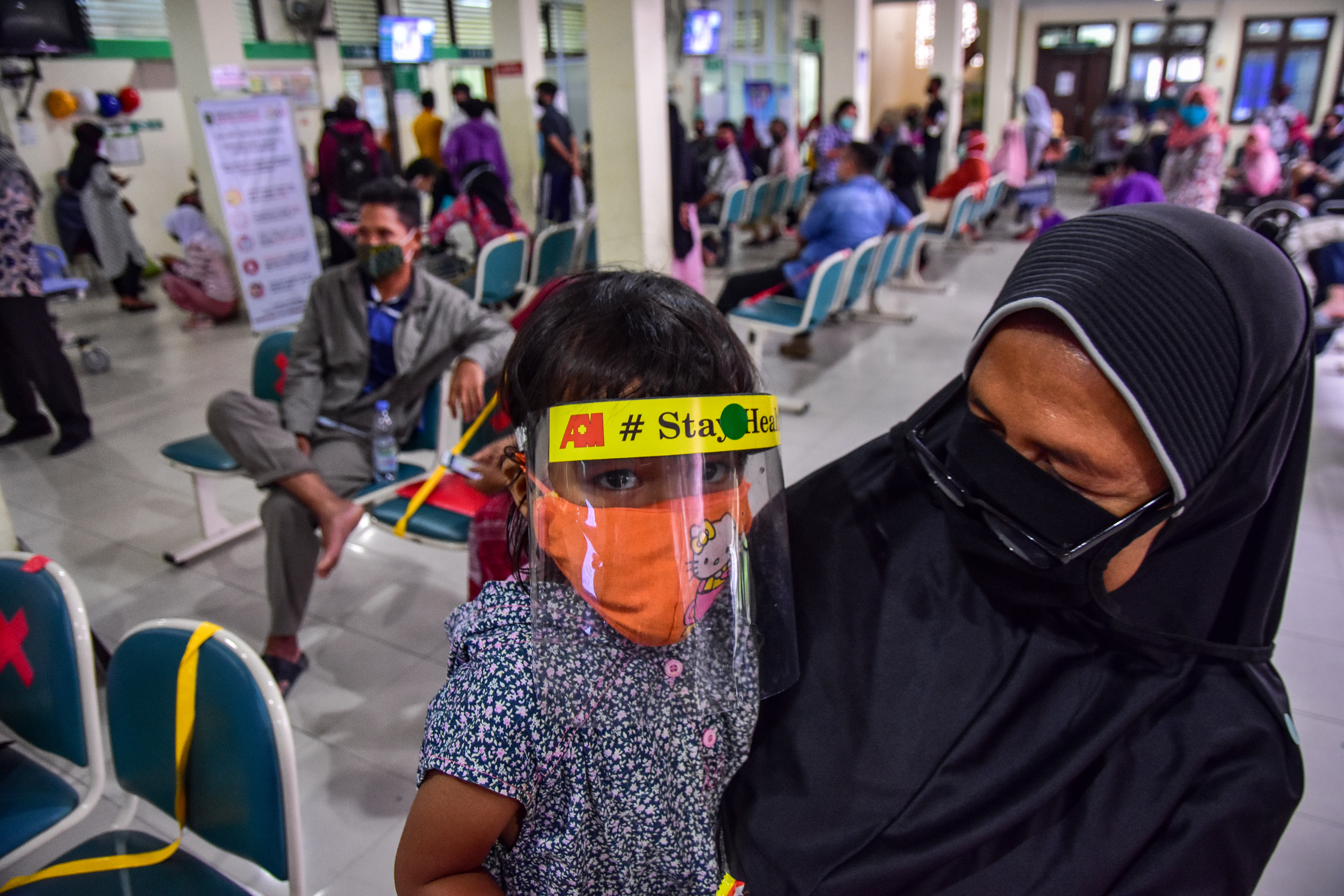Seorang ibu dan anaknya mengenakan alat pelindung diri saat mengantre berobat di RSUD Arifin Achmad, Kota Pekanbaru, Riau, Selasa (14/7/2020