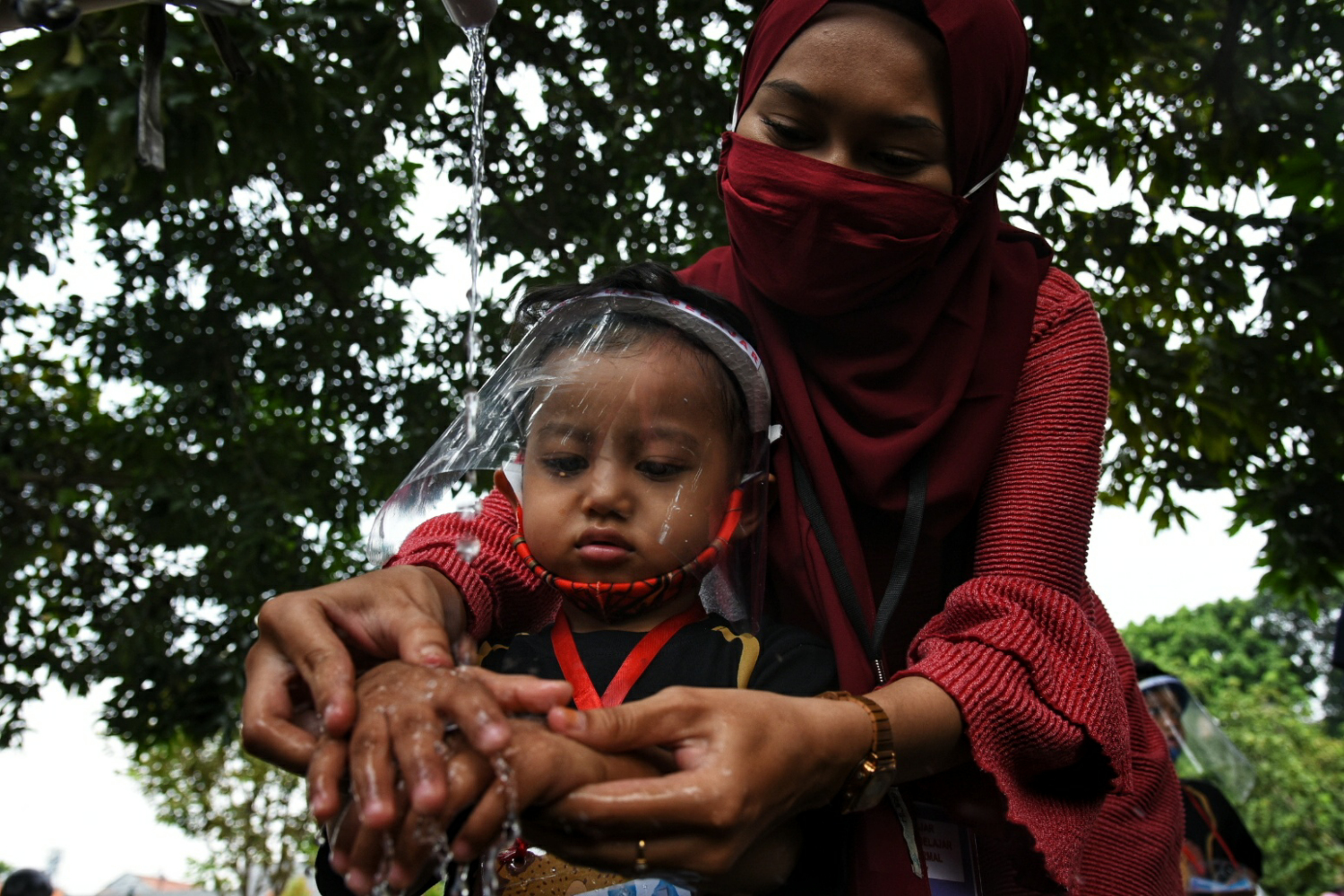 Seorang ibu mengajari anaknya cara membersihkan tangan yang benar untuk mencegah penularan virus covid-19.