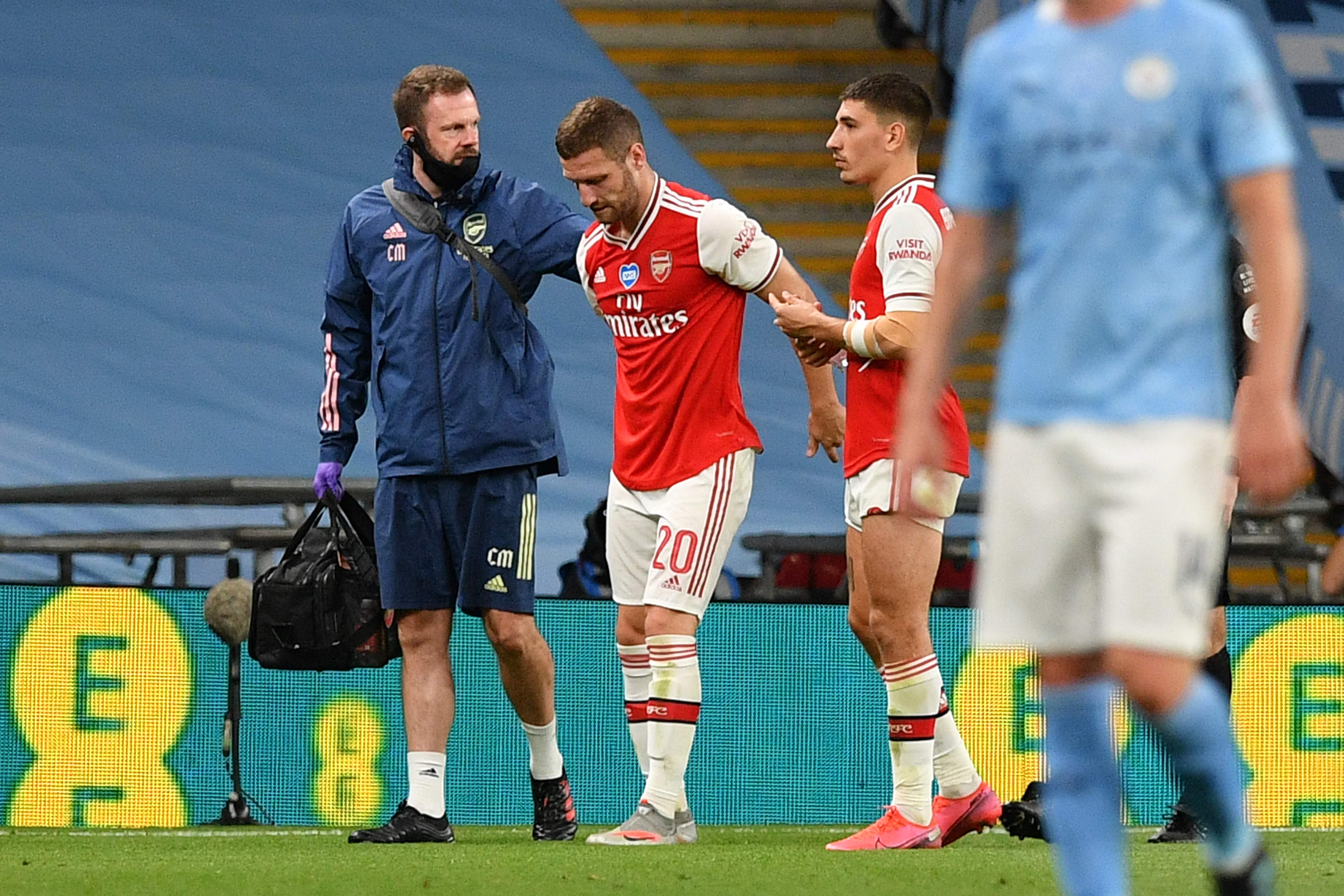 Bek Arsenal Shkodran Mustafi dibantu meninggalkan lapangan setelah mengalami cedera di laga semifinal Piala FA melawan Manchester City.