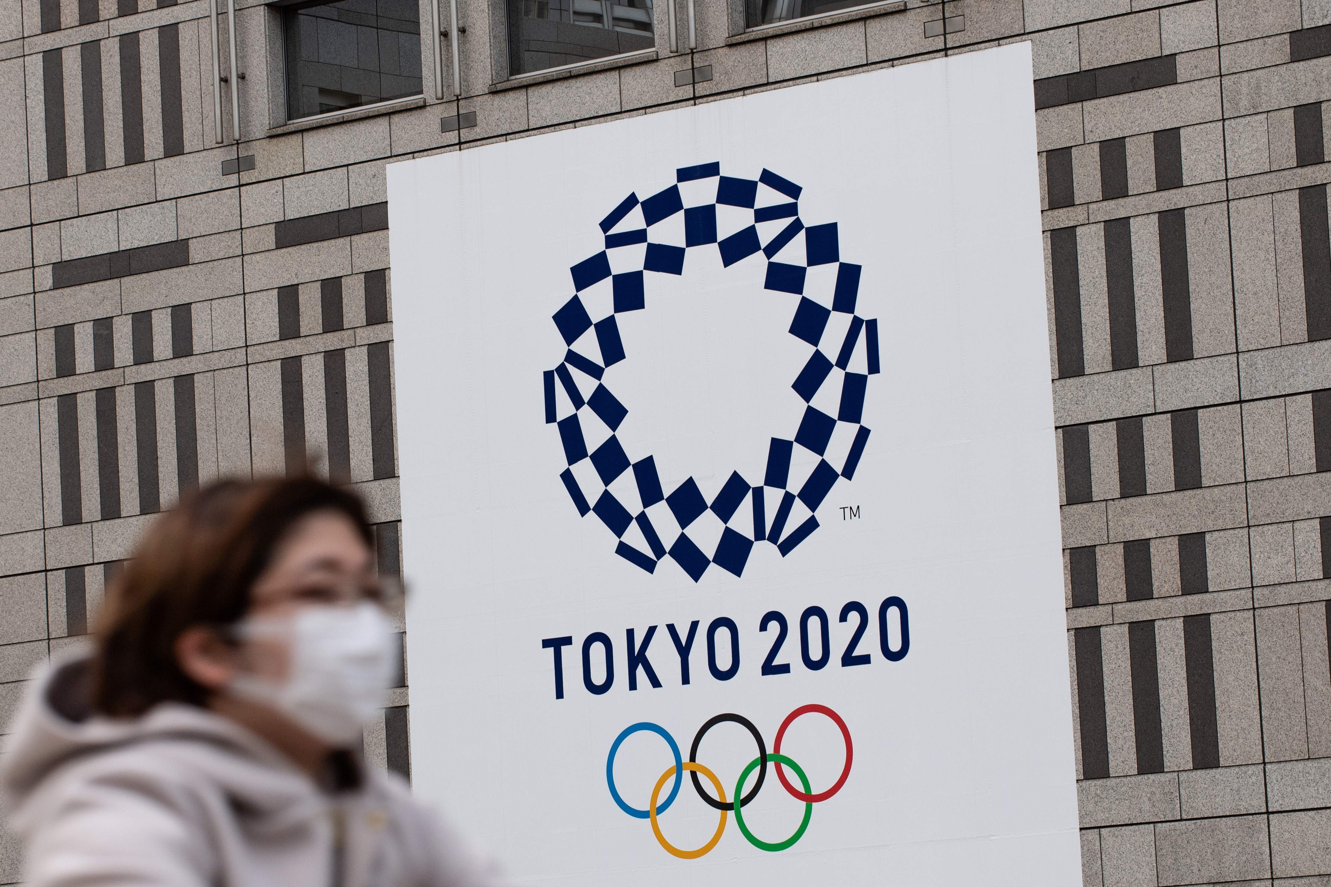Seorang warga melintas di depan logo Olimpiade Tokro 2020 di Tokyo, Jepang.