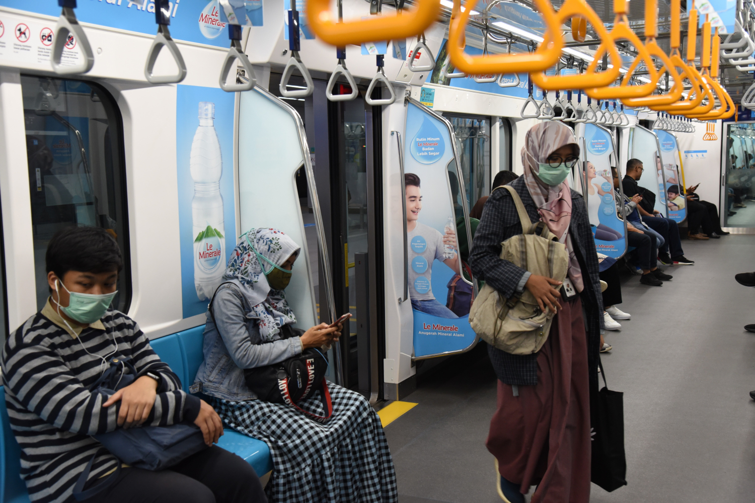 Penumpang MRT melakukan jaga jarak dan mengenakan masker
