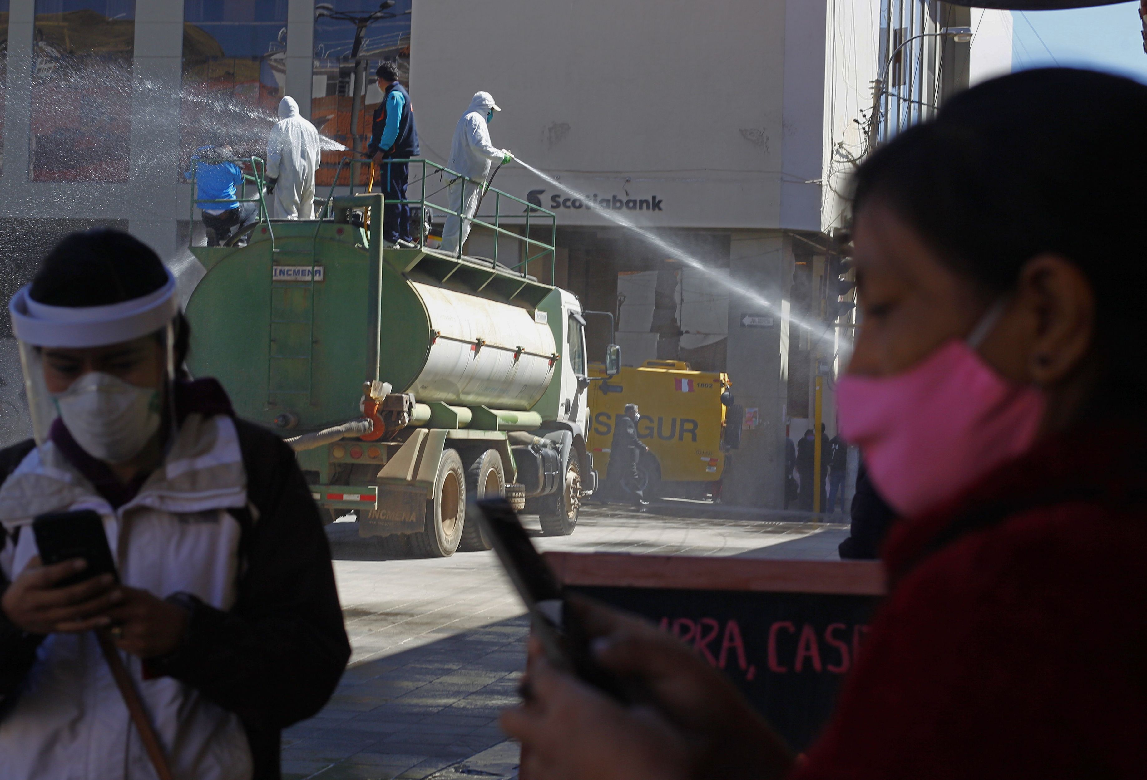 Petugas menyemprotkan cairan disinfektan di jalan Kota Puno, Peru yang berada dekat perbatasan dengan Bolivia.
