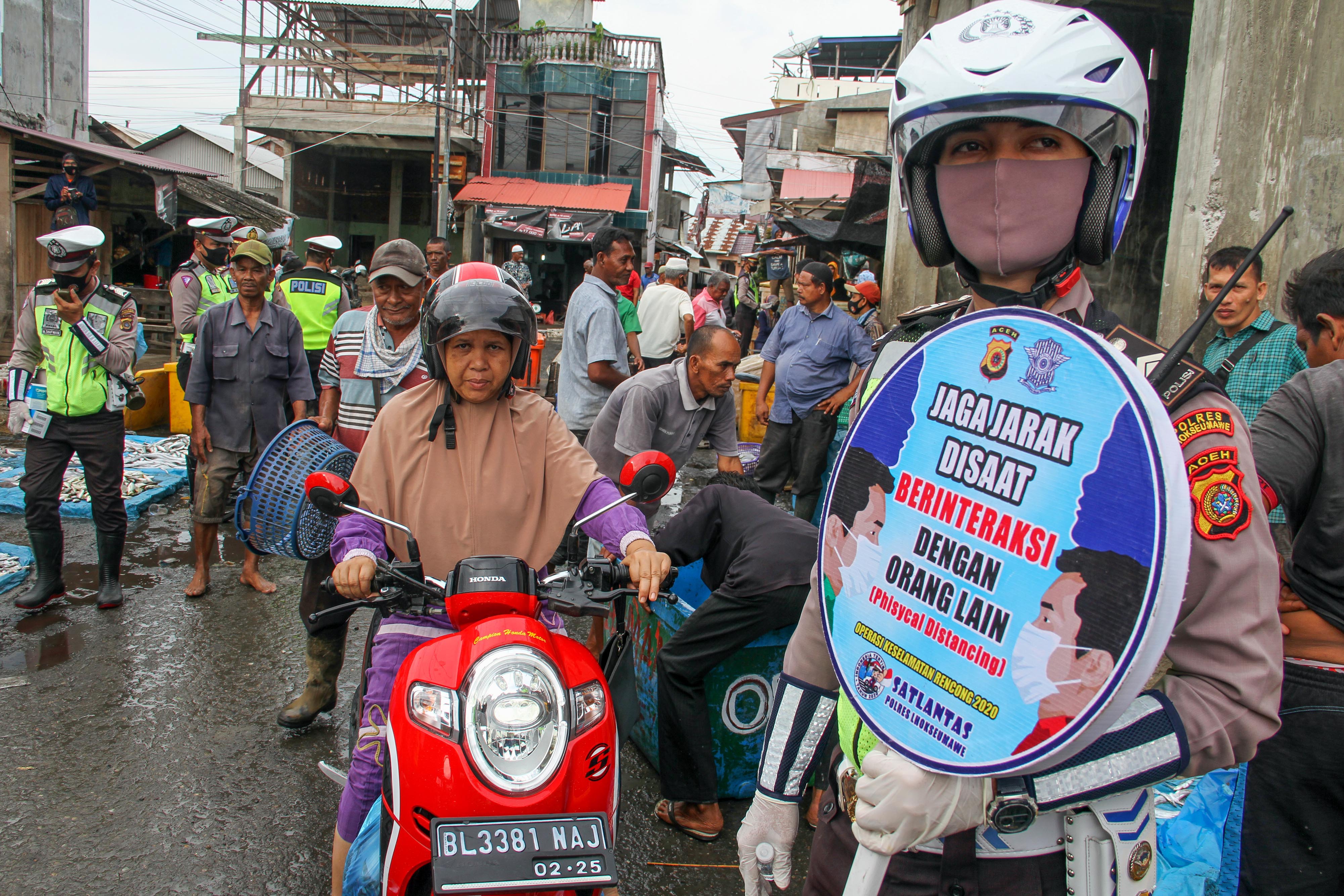 Petugas kepolisian menggencarkan sosialiasi protokol kesehatan di pasar pelelangan ikan, Lhokseumawe, Aceh.