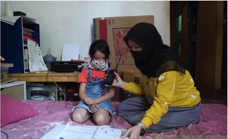 Seorang ibu di Kecamatan Cilaku, Cianjur, mendampingi anaknya saat mendapat materi pelajaran mengunakan HT yang dipinjamkan Polres Cianjur.