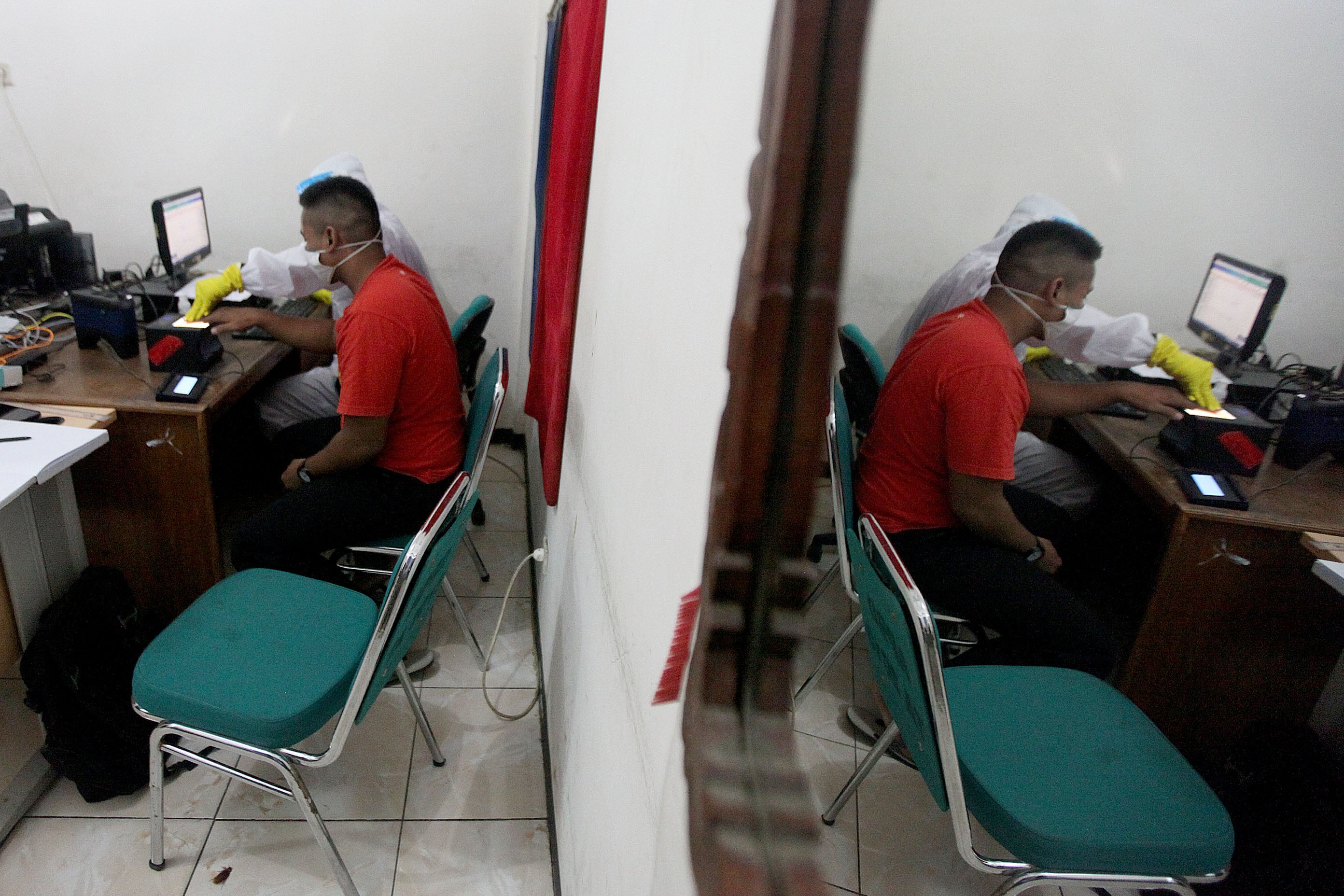 Petugas mengenakan hazmat saat proses perekaman KTP Elektronik di Kecamatan Pamulang, Tangerang Selatan, Banten.