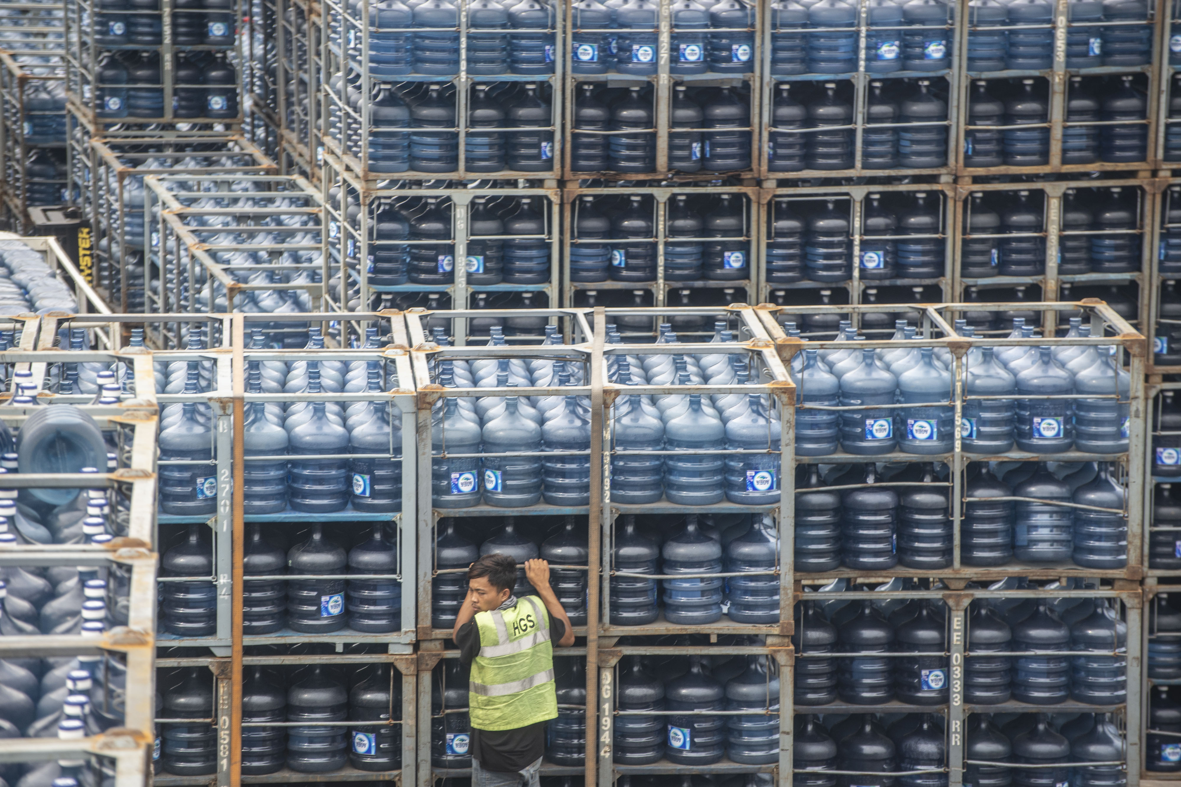 Pekerja melakukan aktivitas bongkar muat air minum dalam kemasan di Jakarta.