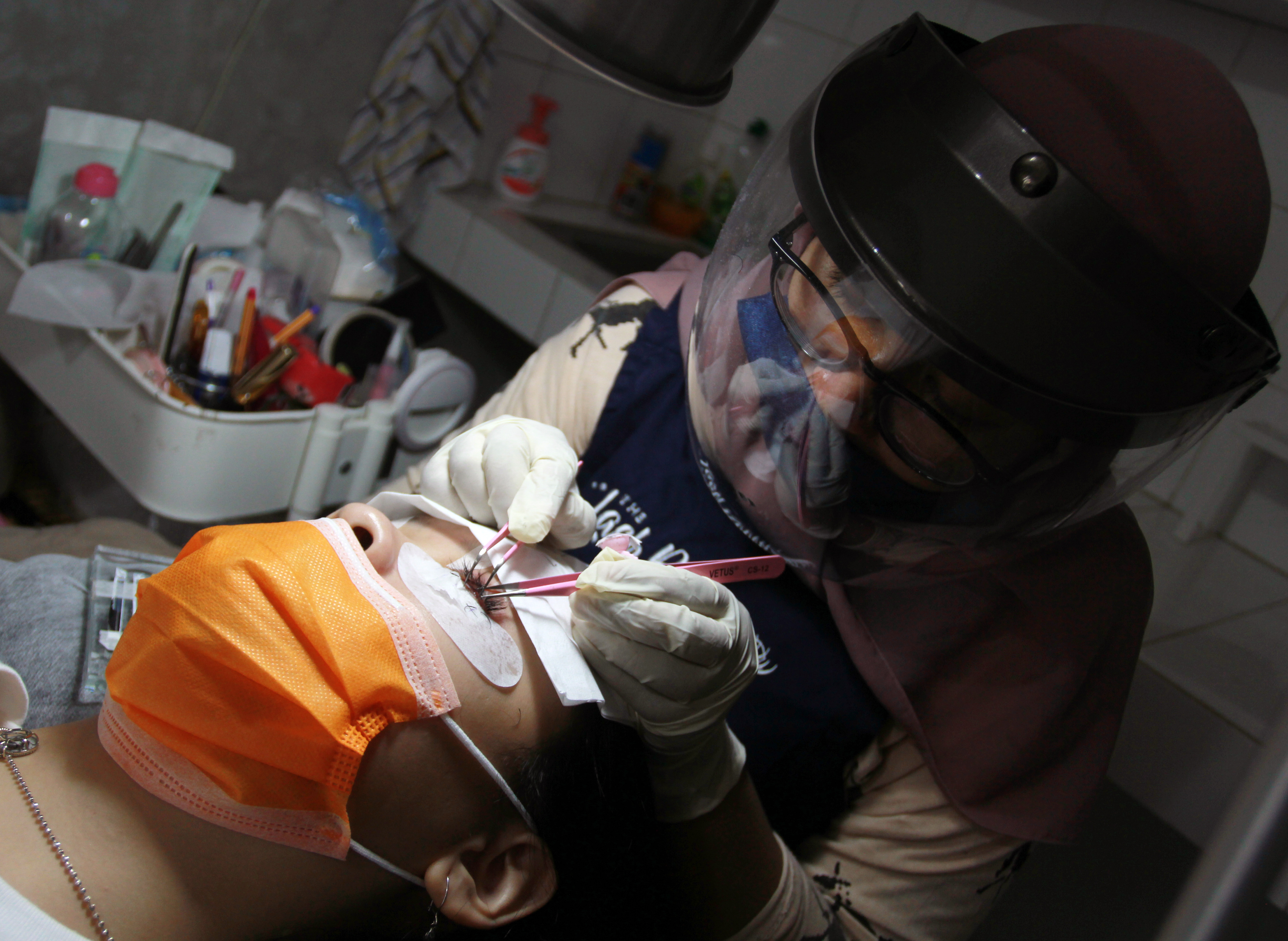 Ahli kecantikan dengan protokol kesehatan ketat melakukan sambung bulu mata di The Lash Room Palm Residence Tangerang, Banten, Selasa (14/7)