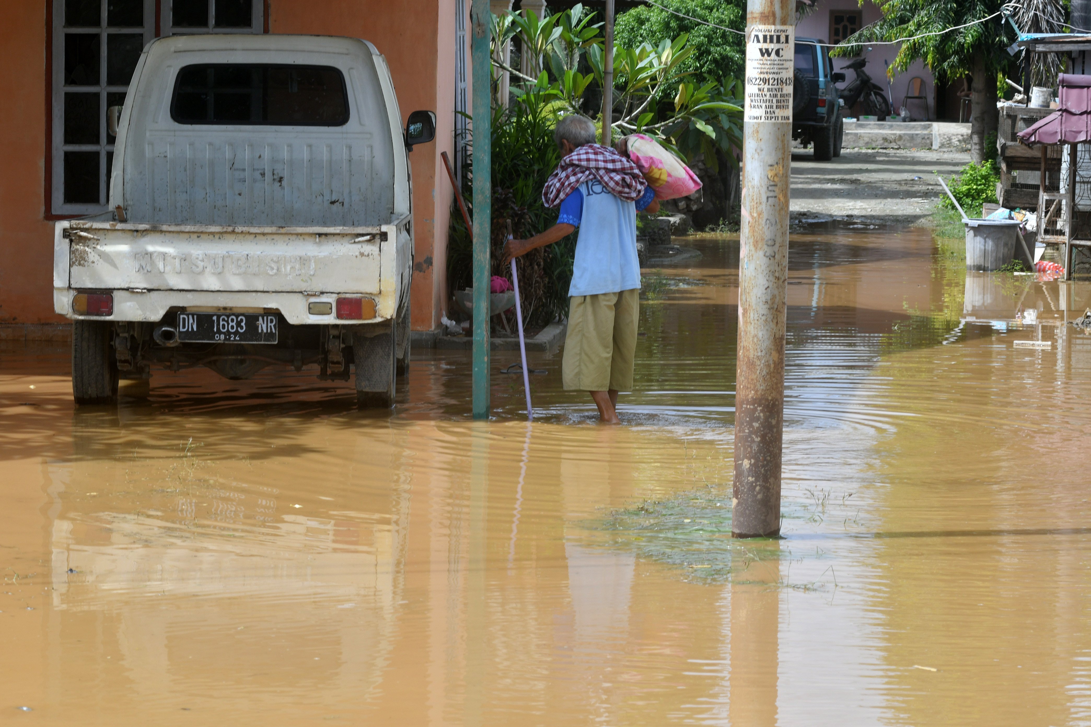 Warga berada di halaman rumahnya yang dipenuhi genangan air di Palu, Sulawesi Tengah, Selasa (14/7).