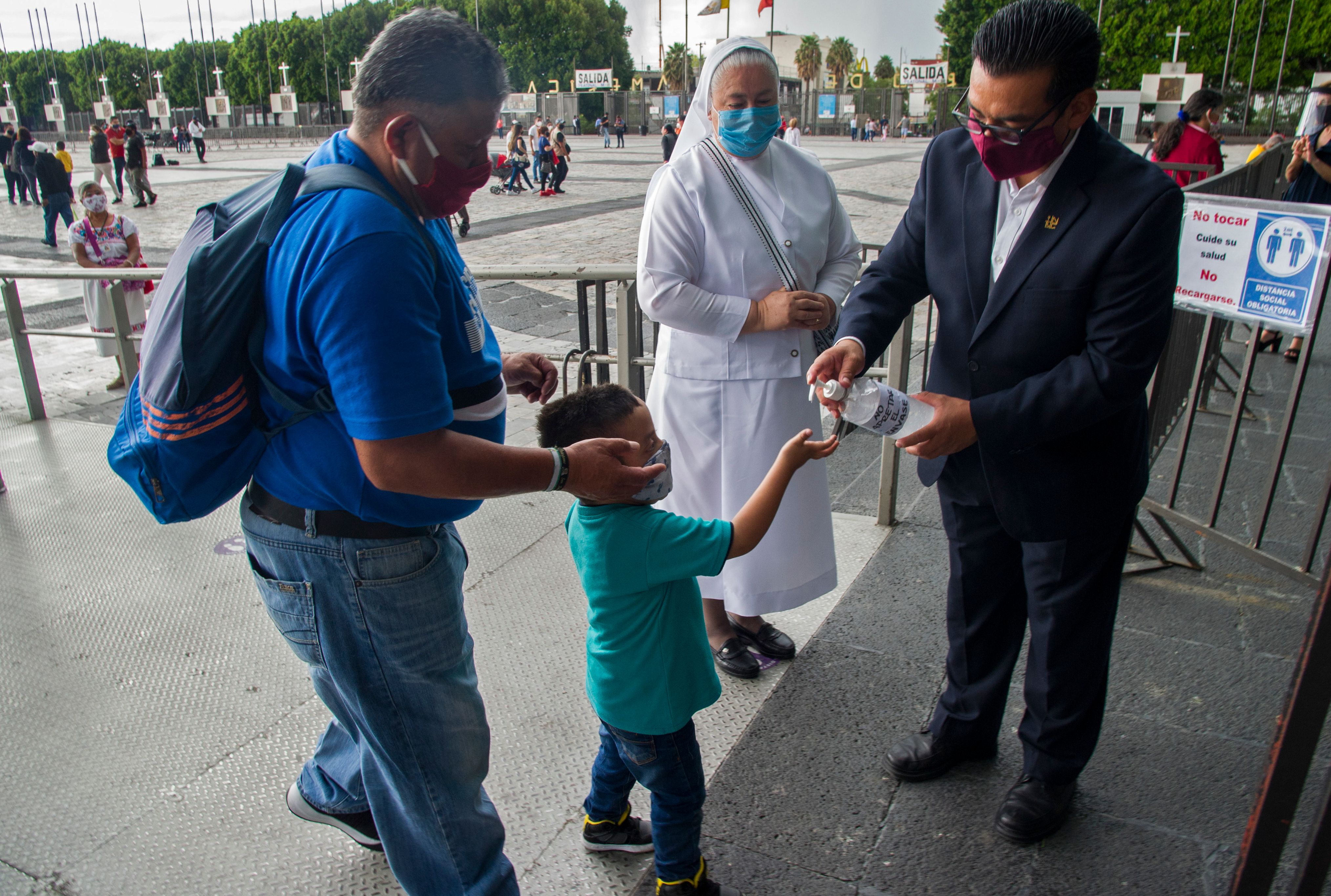 Petugas menuangkan hand sanitizer kepada umat yang datang ke Basilica of Guadalupe, Mexico City untuk mengikuti misa pertama pascalock down.