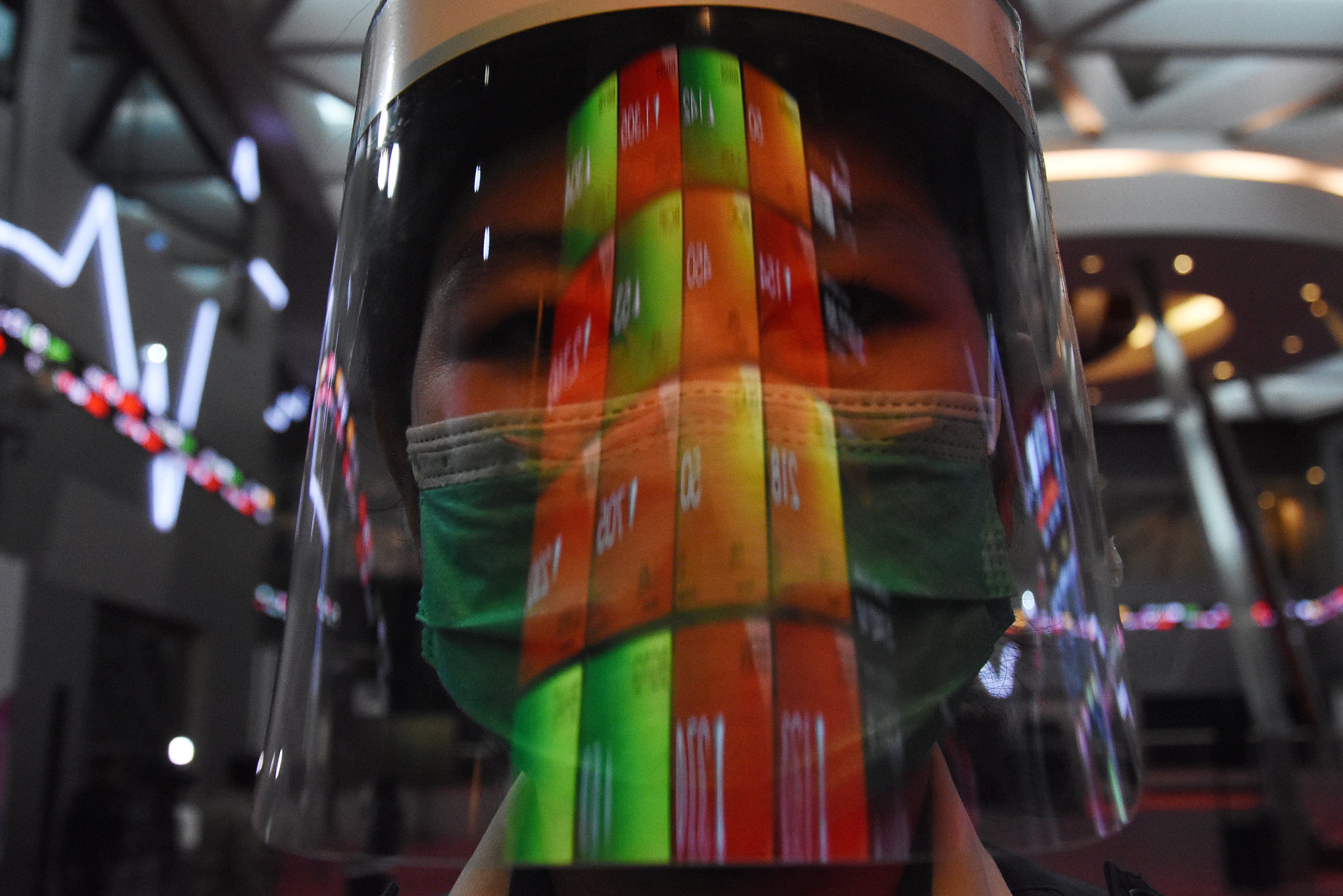 Layar pergerakan IHSG yang terpantul dari face shield yang dikenakan karyawan di BEI.