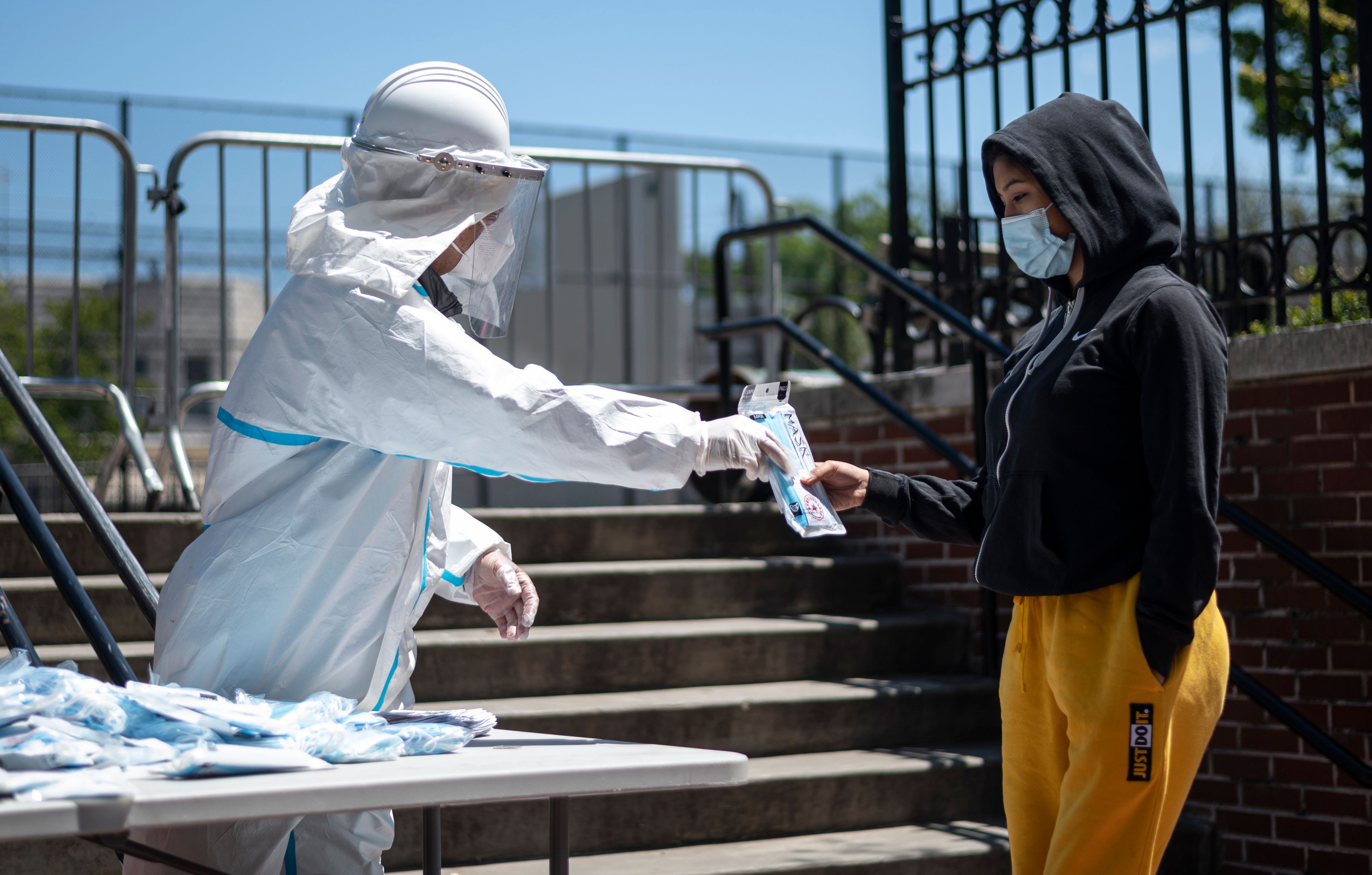 Seorang pria membagikan masker kepada pejalan kaki di New York, AS.  AS telah melaporkan sebagian besar kasus dan jumlah kematian tertinggi.